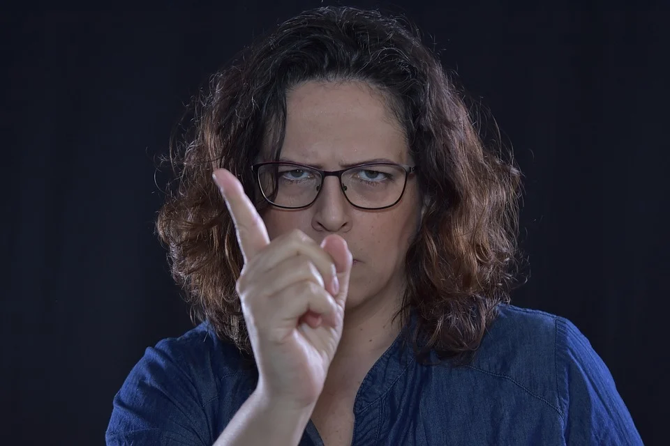 Una mujer enojada con anteojos recriminando con su dedo índice. | Foto: Pixabay