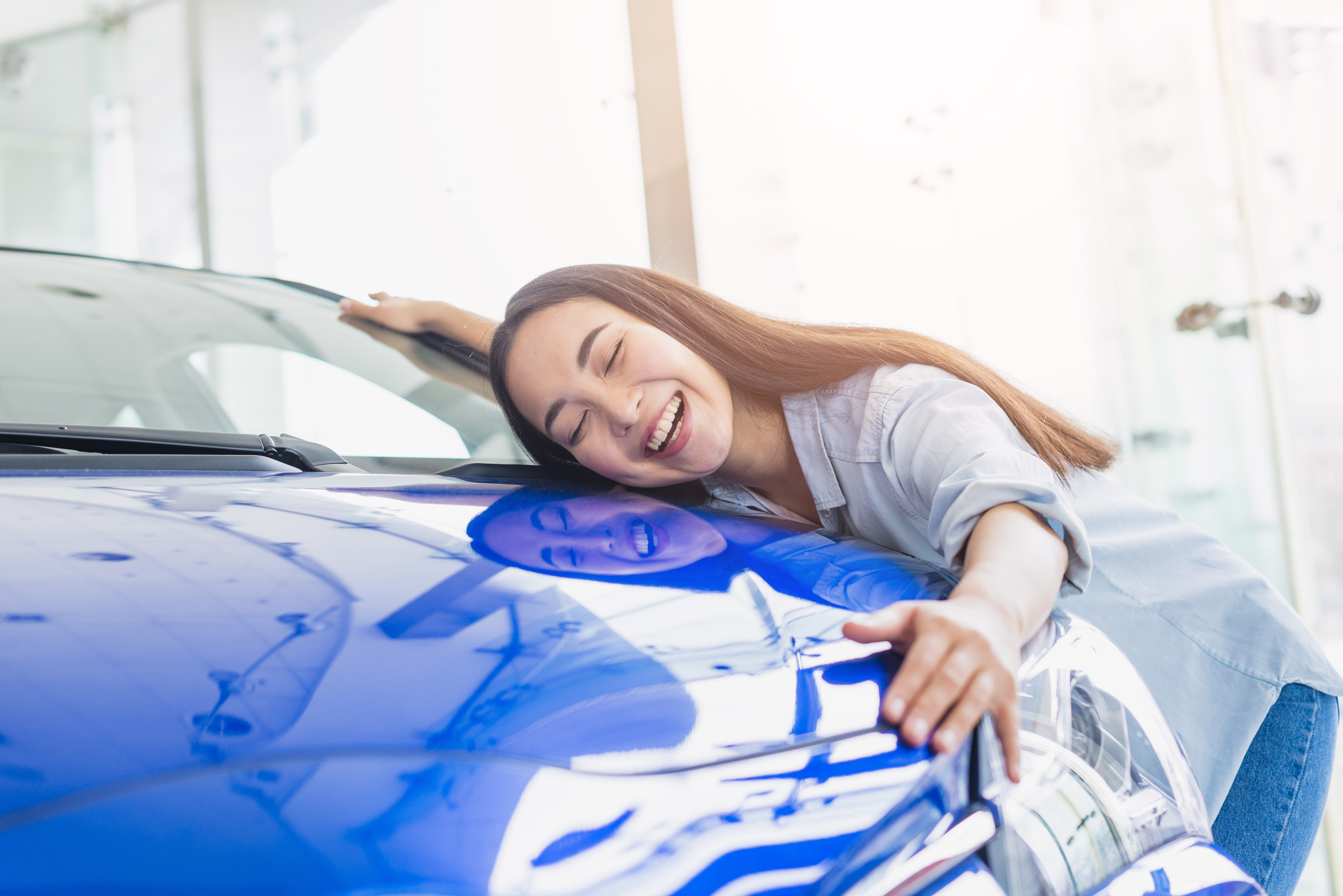 Niña abrazando el capó de un coche azul | Fuente: Freepik