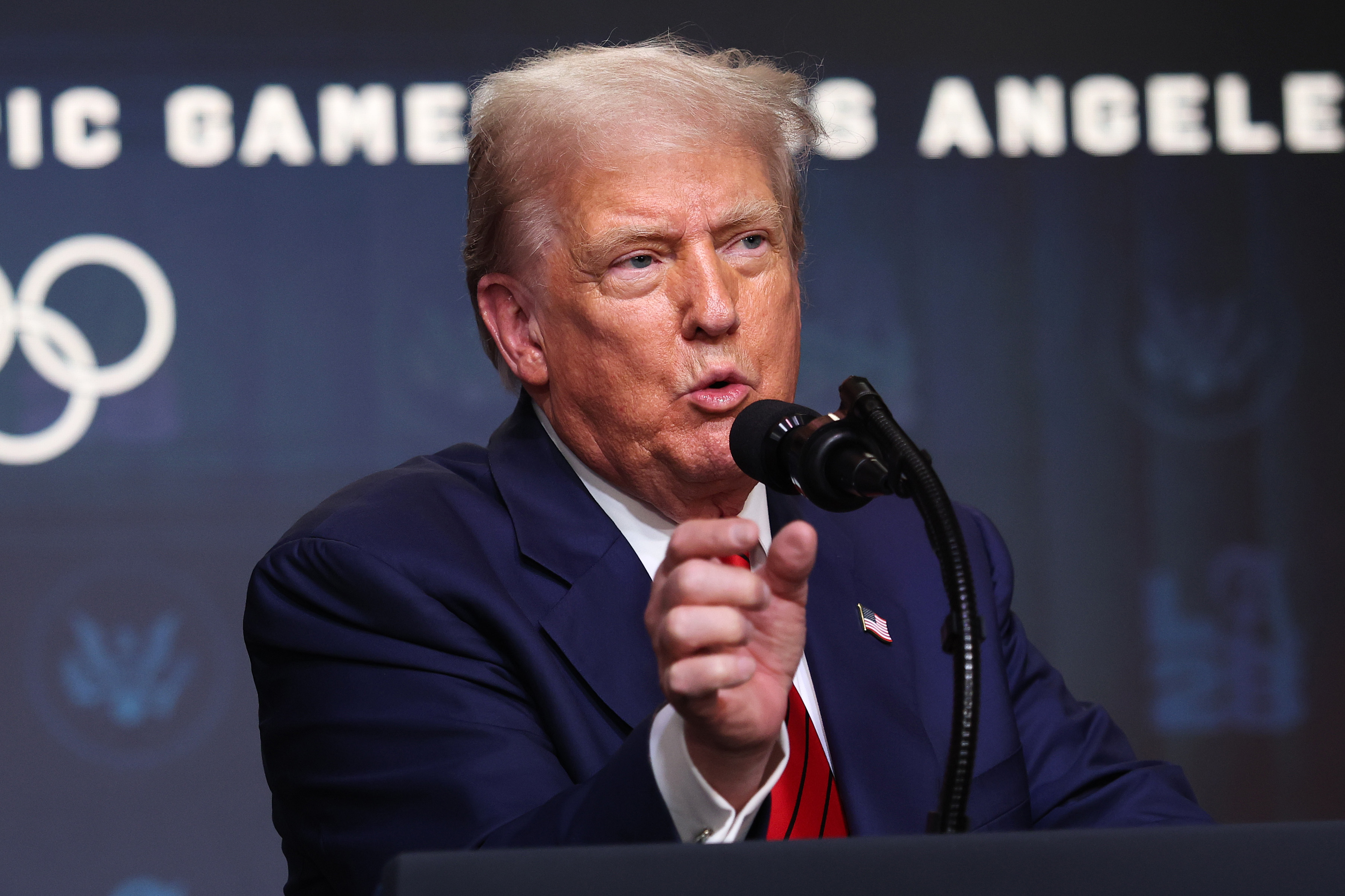 Speaking into the microphone, Donald Trump addresses the press after signing an executive order in the South Court Auditorium, outlining plans to back the 2028 Los Angeles Olympics.