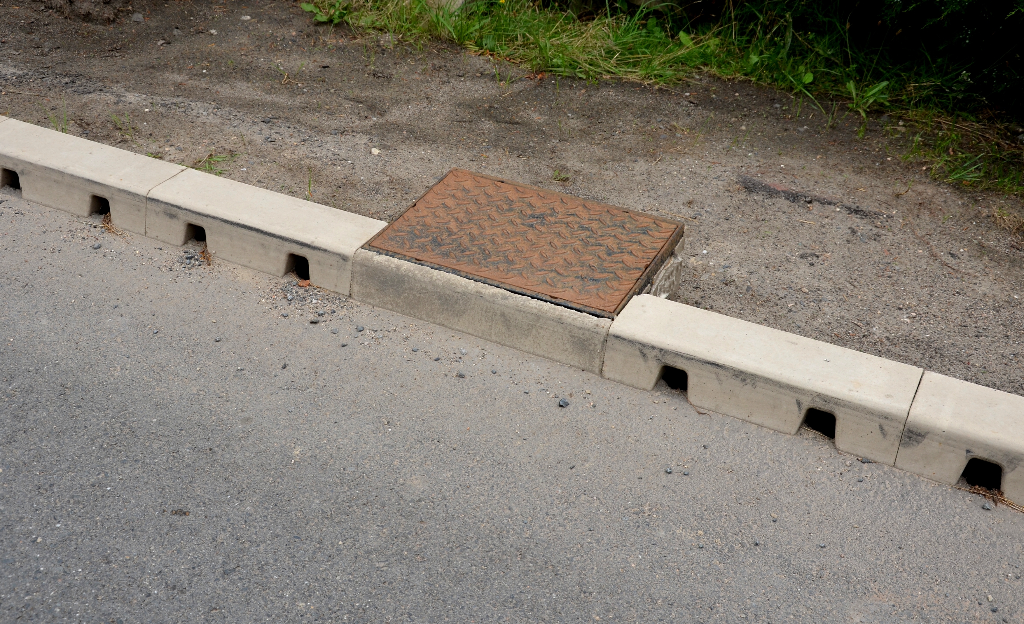 Drainage hidden on the edge of an asphalt road. | Source: Shutterstock