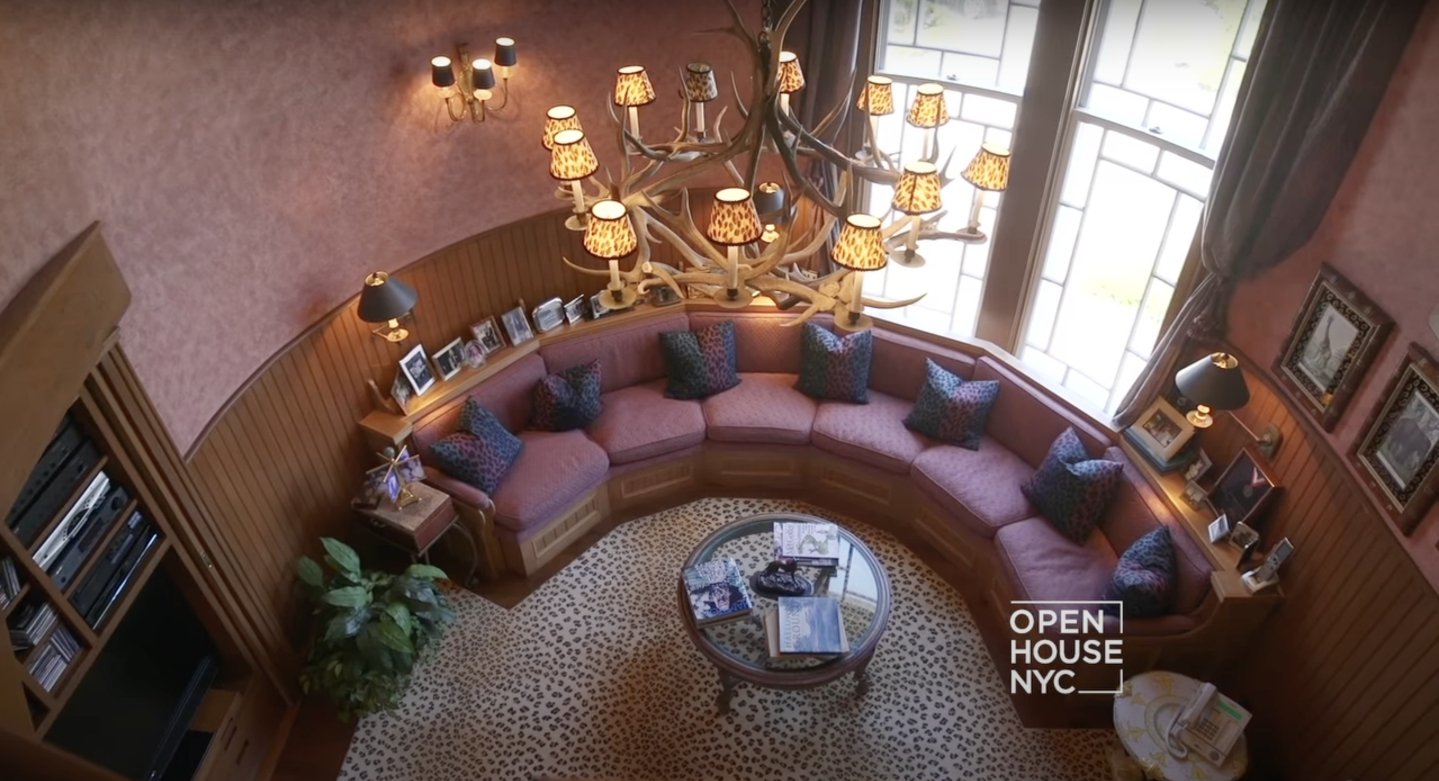 The room where visitors often gathered which showcased a center rug, tabletop decorations, a few pieces of paintings, neatly arranged chairs with wooden legs and fine cushions/ pillows, and a center table that marched the chandelier. | Source: youtube.com/Open House TV