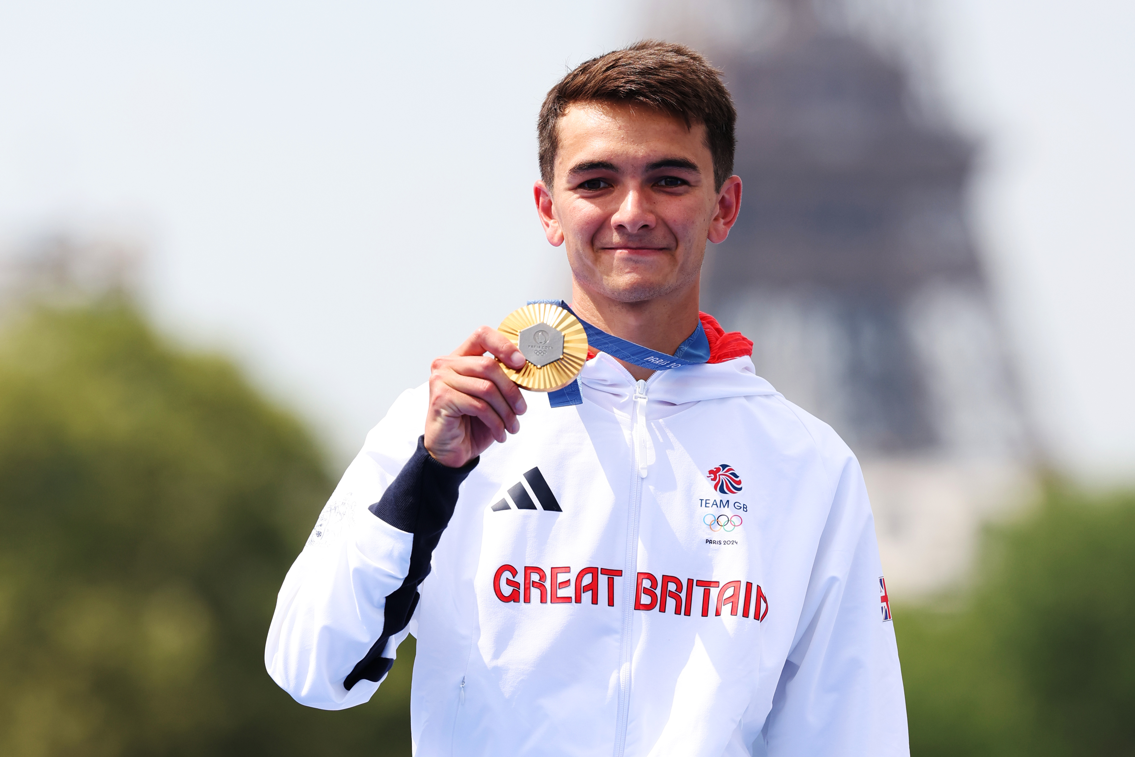 Alex Yee shows his gold medal on the podium during the Triathlon medal ceremony after the Men's Individual event on July 31, 2024 | Source: Getty Images