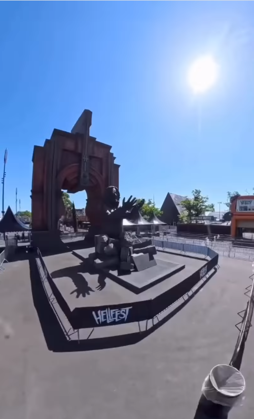 Ozzy Osbourne's "Prince of Darkness" statue is displayed at Hellfest in Clisson, France, beneath a towering archway featuring the festival's emblem. The monument sits on a raised platform under clear skies ahead of its official unveiling. | Source: Instagram/sharonosbourne