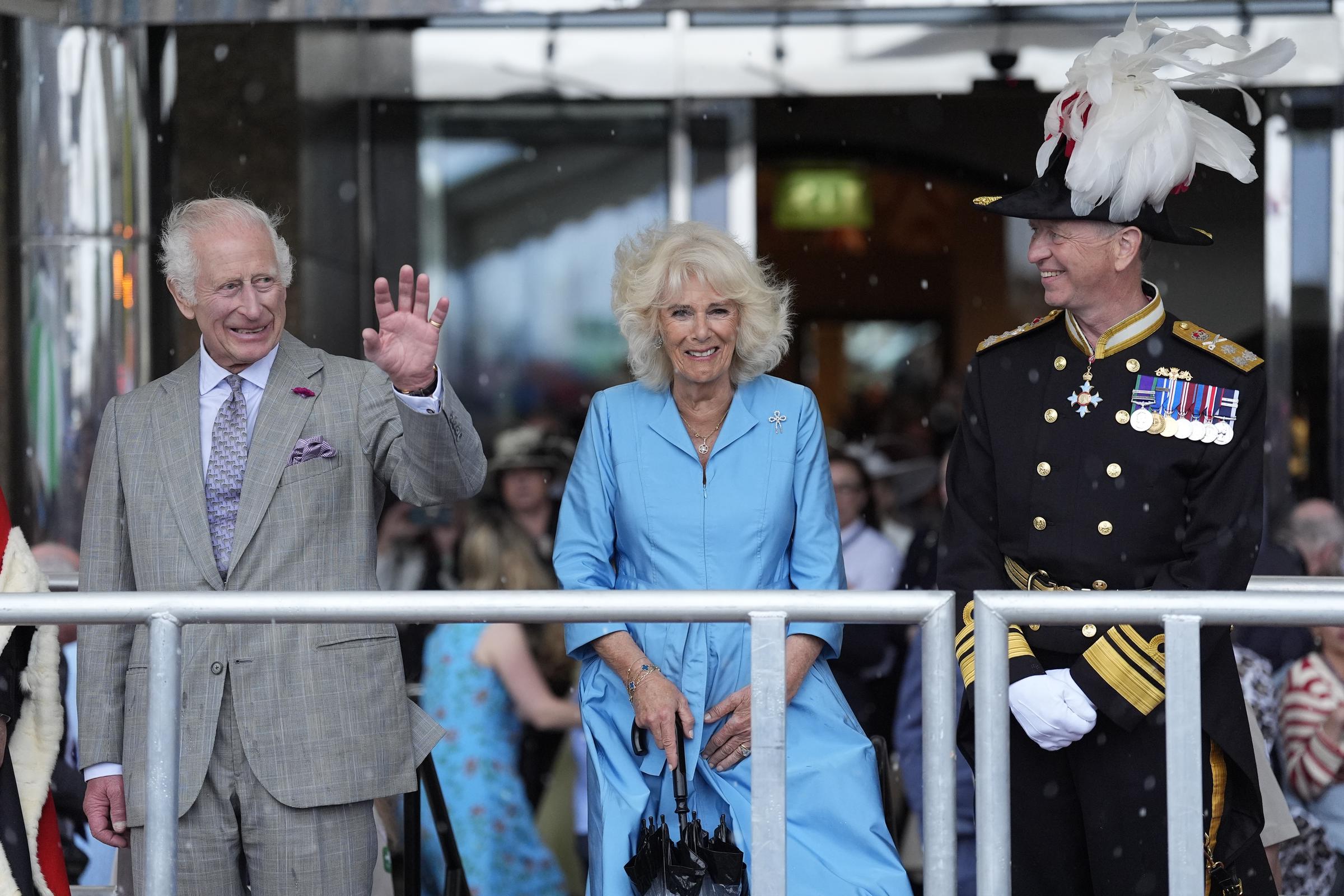 King Charles III waves while Queen Camilla smiles next to Lieutenant-Governor of Jersey Vice Admiral Jerry Kyd outside Pomme d'Or Hotel, Liberation Square in St. Helier, Jersey on July 15, 2024. | Source: Getty Images