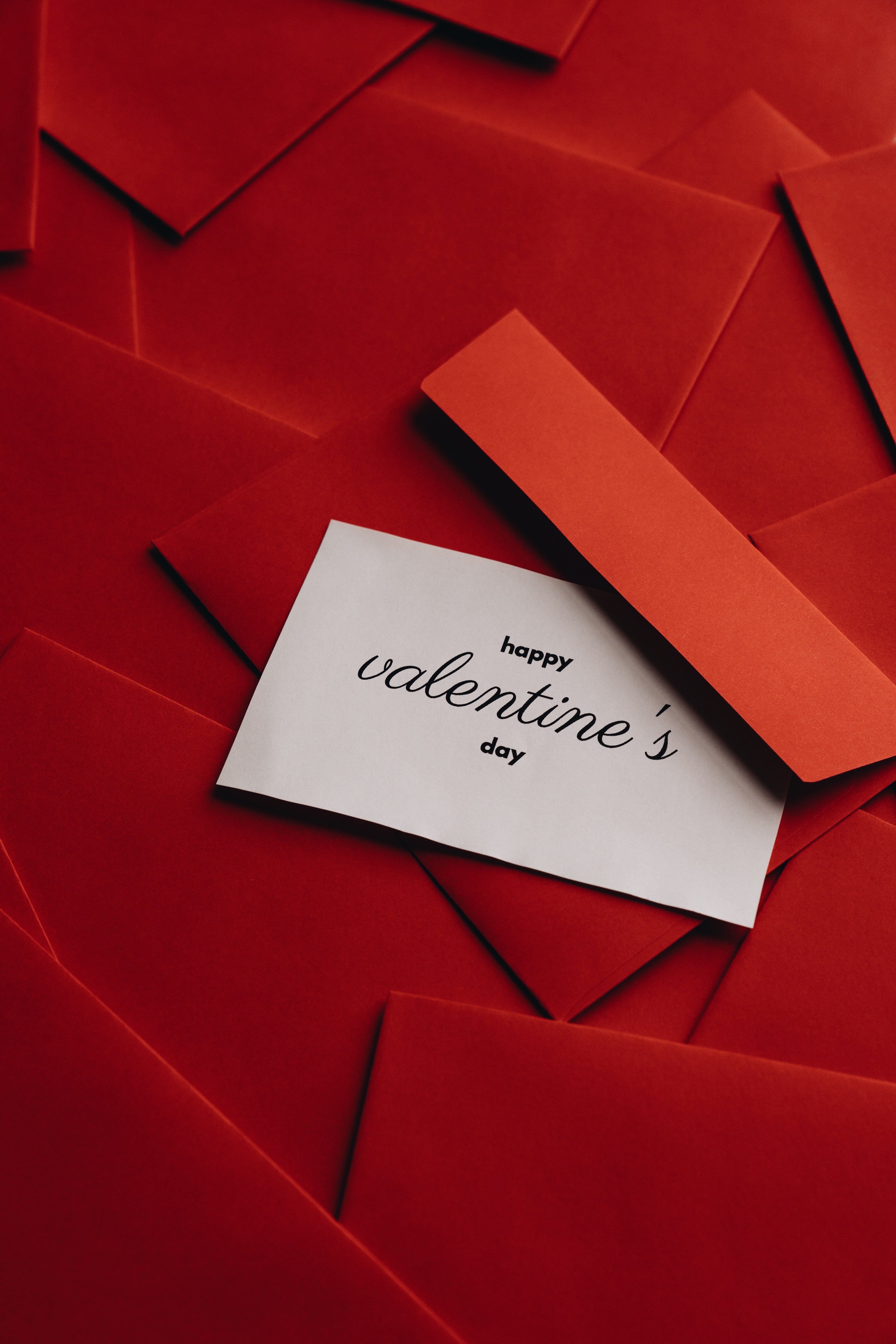 A white Valentine's note ontop of red envelopes. | Photo: Pexels.