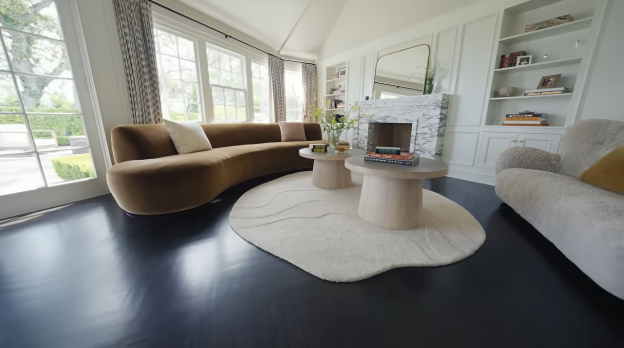 Worth the splurge! This gorgeous fireplace setup features a curved vintage velvet sofa that Palmer famously moved out of her bedroom to make room for her fitness routine. | Source: YouTube/@Archdigest