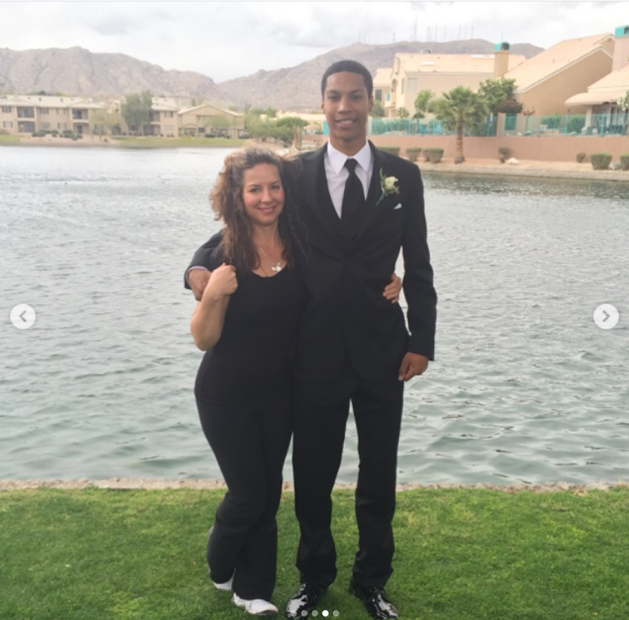 A young Brandon Clarke poses beside his mother, Whitney Triplett, near a lakeside setting while dressed in a black suit and tie for a formal occasion. | Source: Instagram/brandon_clarke23
