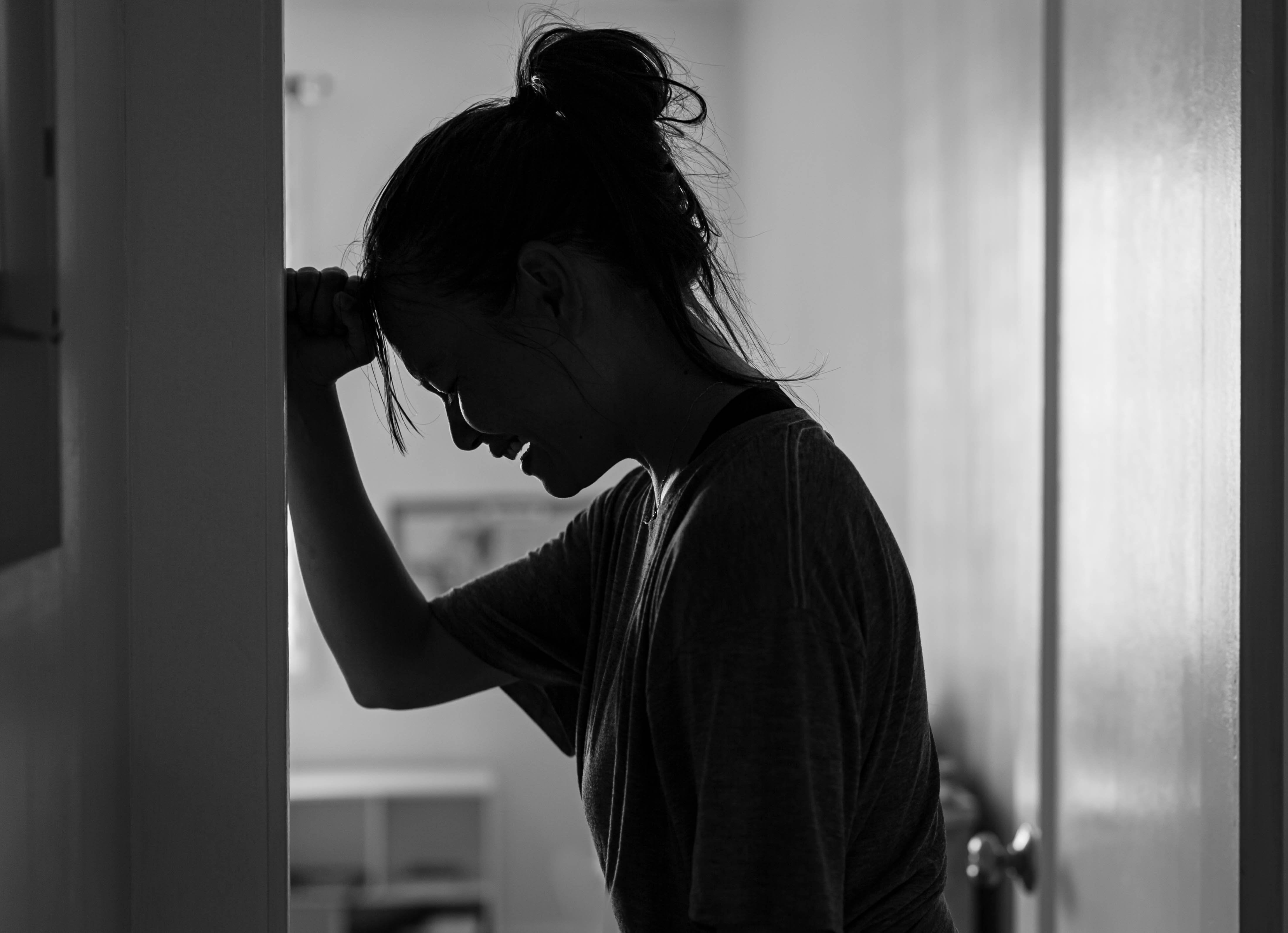 Eine traurige Frau, die allein zu Hause in ihrem Zimmer weint und deprimiert ist. | Quelle: Shutterstock