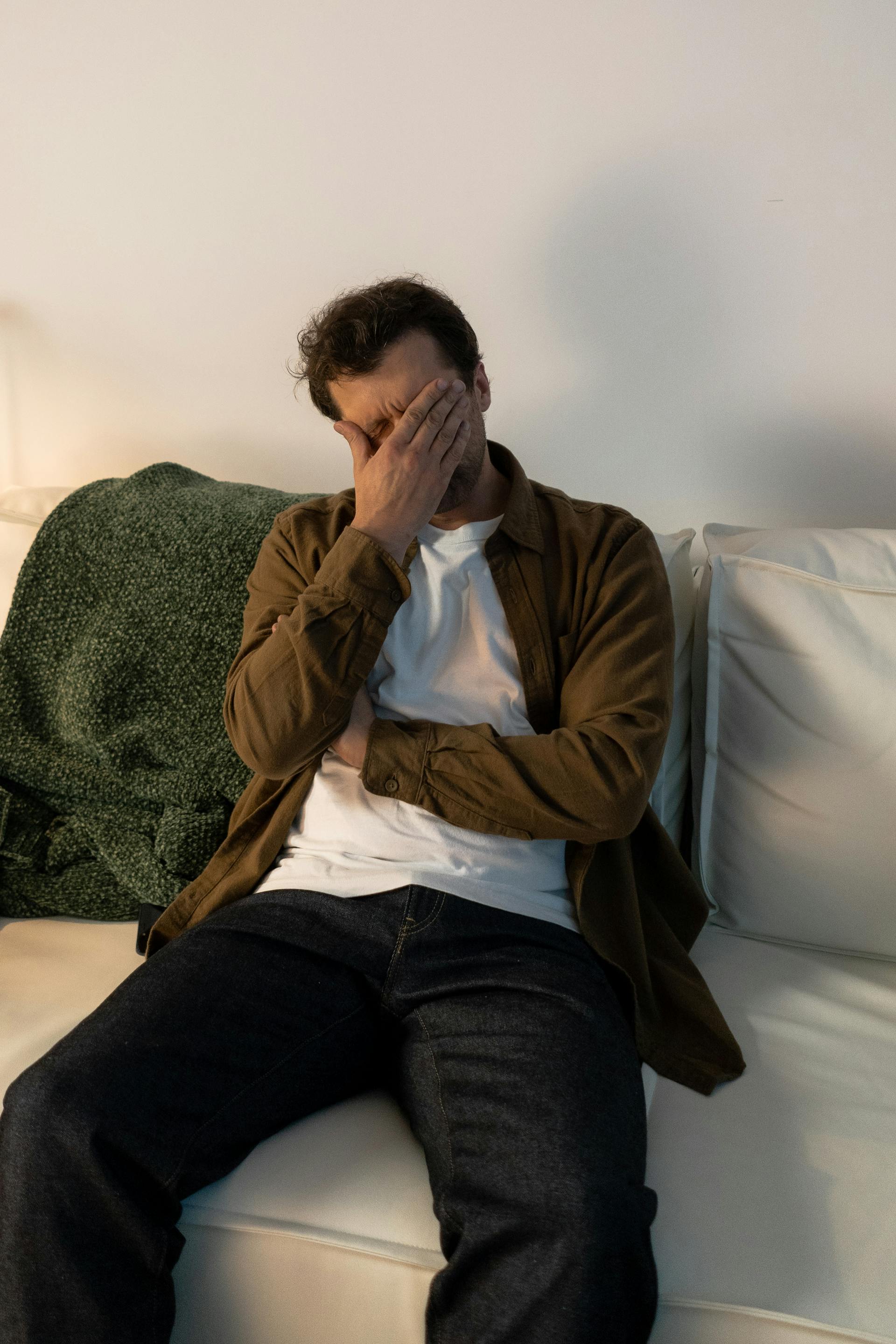 A distressed man sitting on a couch | Source: Pexels