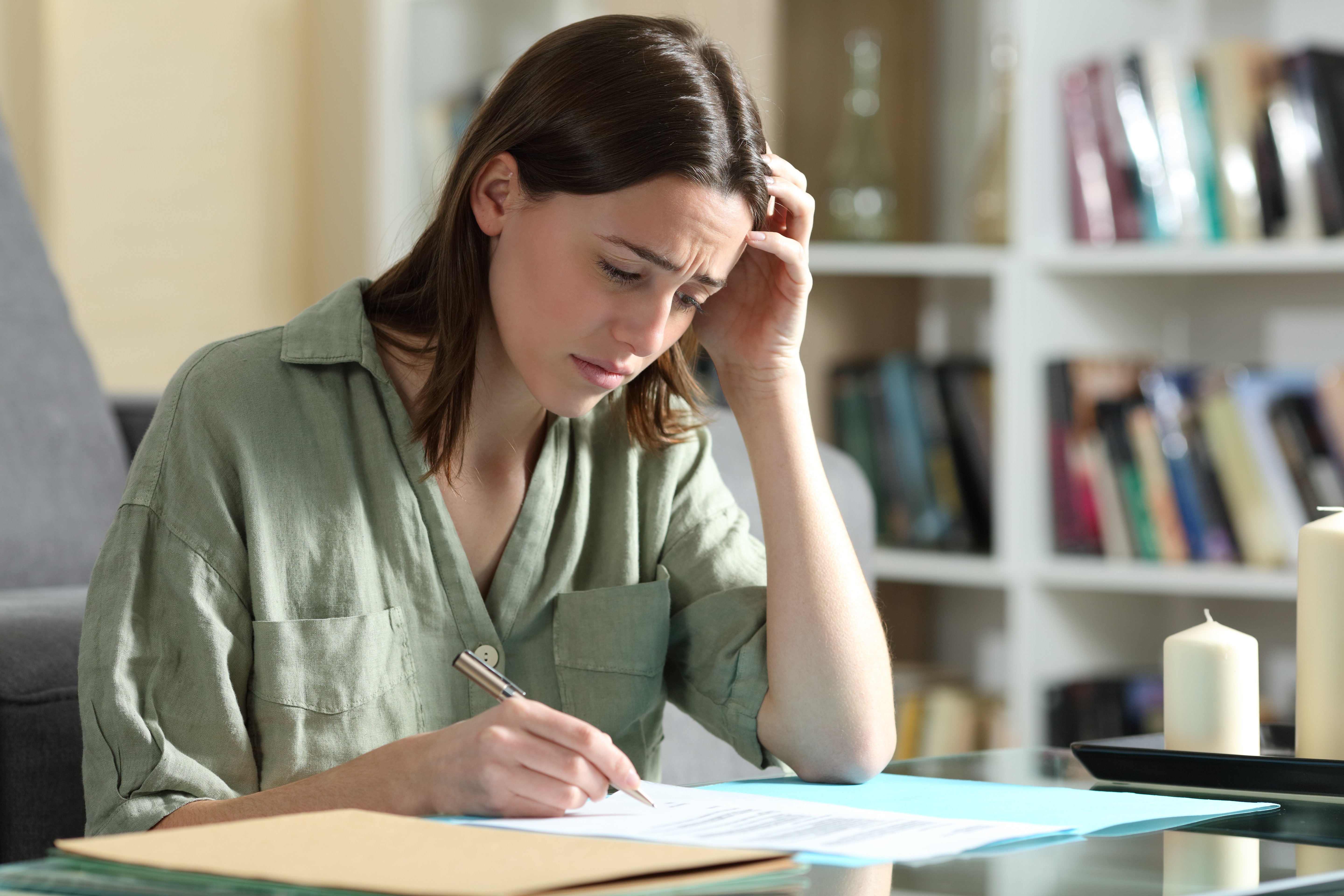 Mujer triste firmando papeles. | Foto: Shutterstock