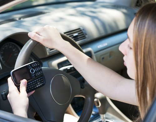 A teenage girl texting and driving. | Source: Shutterstock.