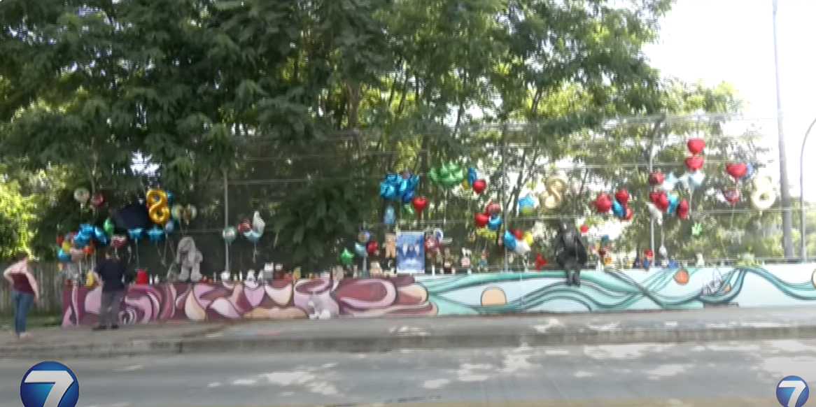 The memorial site on McClure Street near U.S. 35, where people have left flowers, balloons, stuffed animals, and handwritten signs,