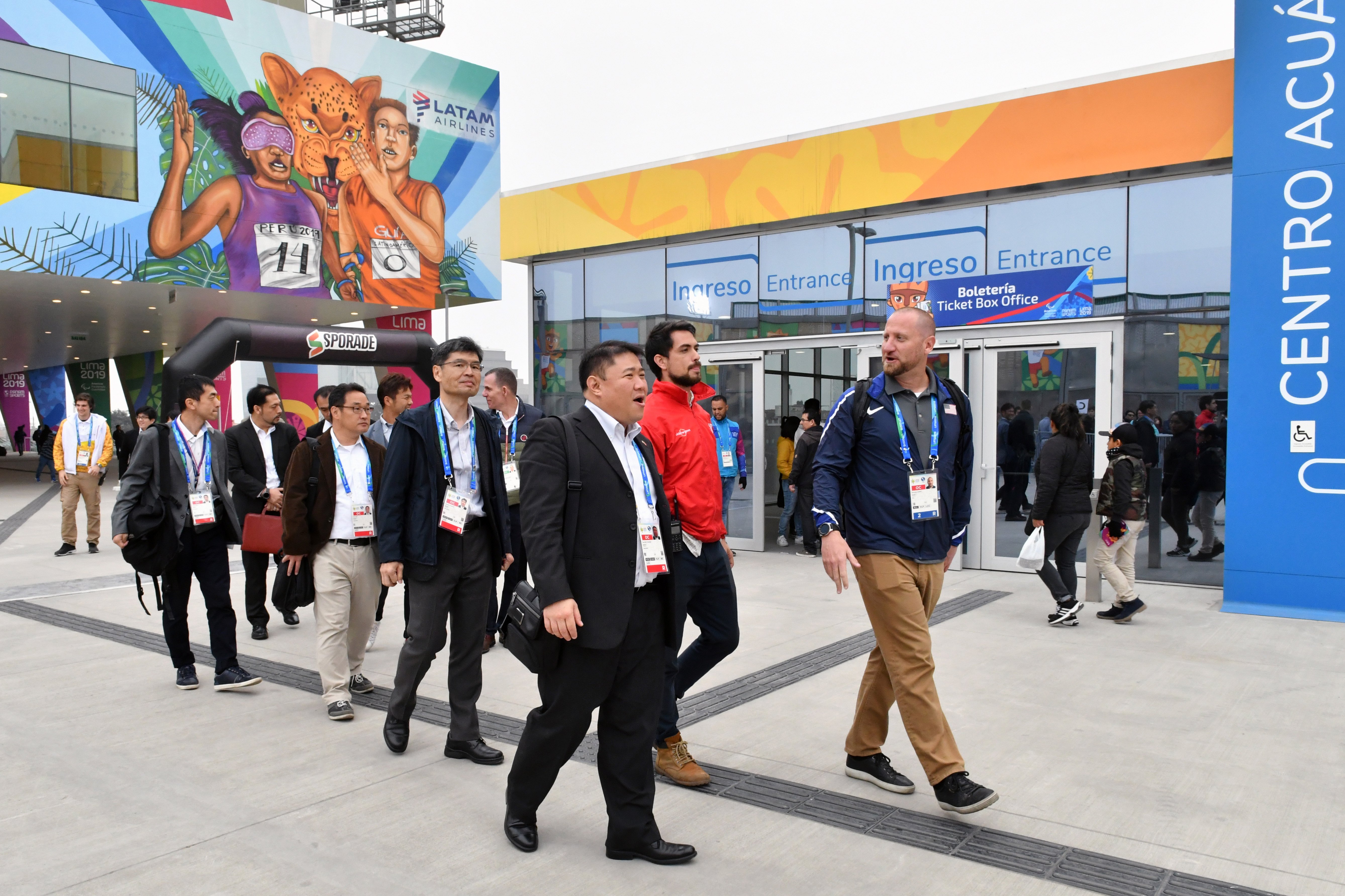 A Diplomatic Security Service special agent leads a Japanese delegation on a tour of the Videna Multi-Sport complex, Lima, Peru, August 2019. | Source: Wikimedia Commons