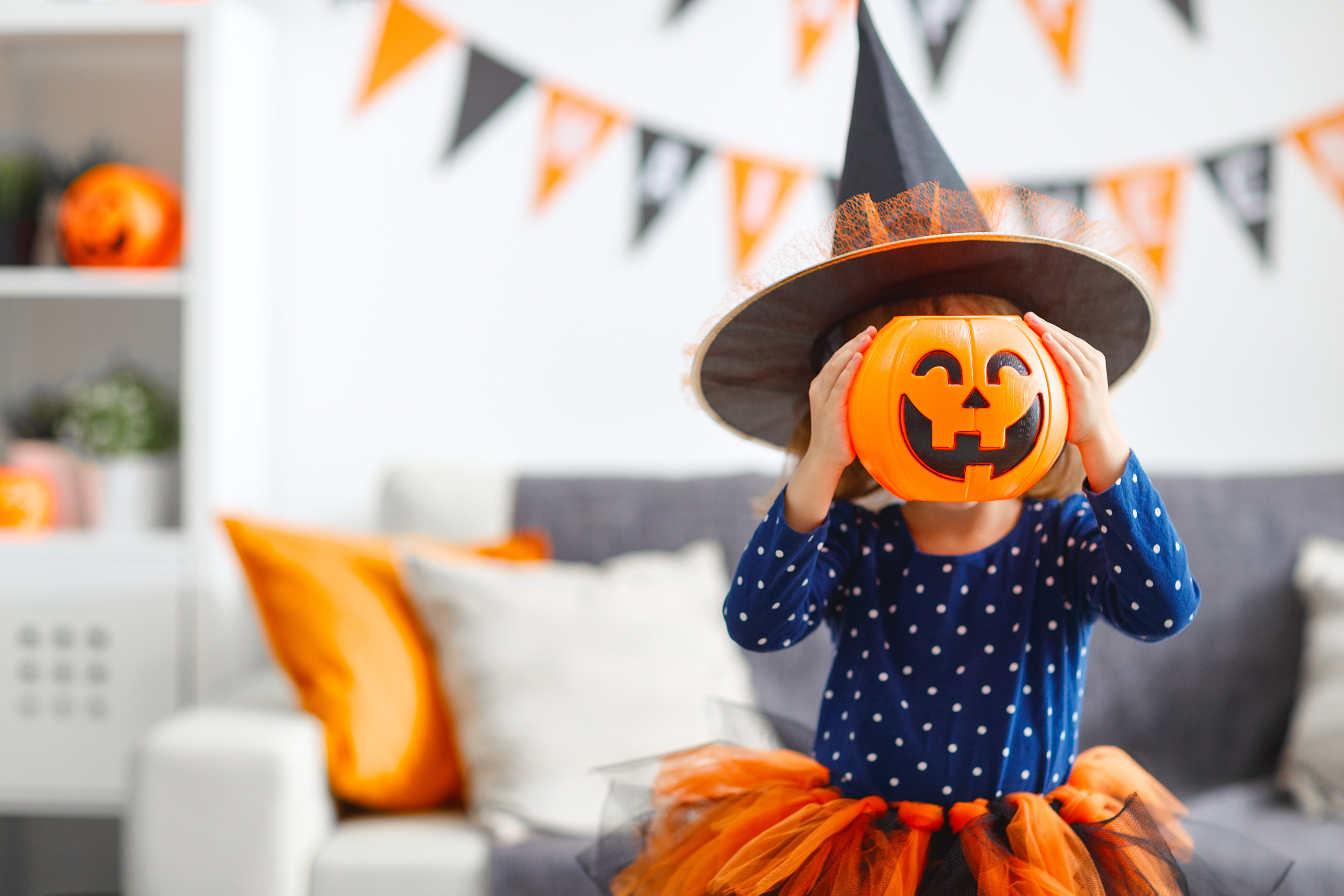 Niña luciendo un disfraz con sombrero de bruja y máscara de calabaza de Halloween. | Foto: Shutterstock