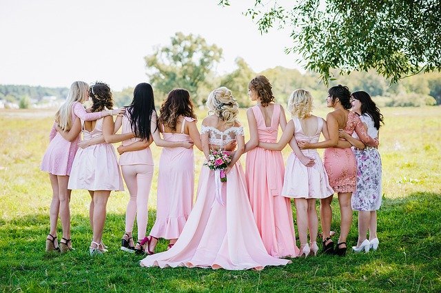 A bride and her bridesmaids pose on meadow | Photo: Pixabay