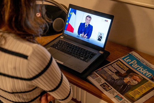 Un citoyen regarde le président français Emmanuel Macron sur un écran d'ordinateur. |Photo : Getty Images