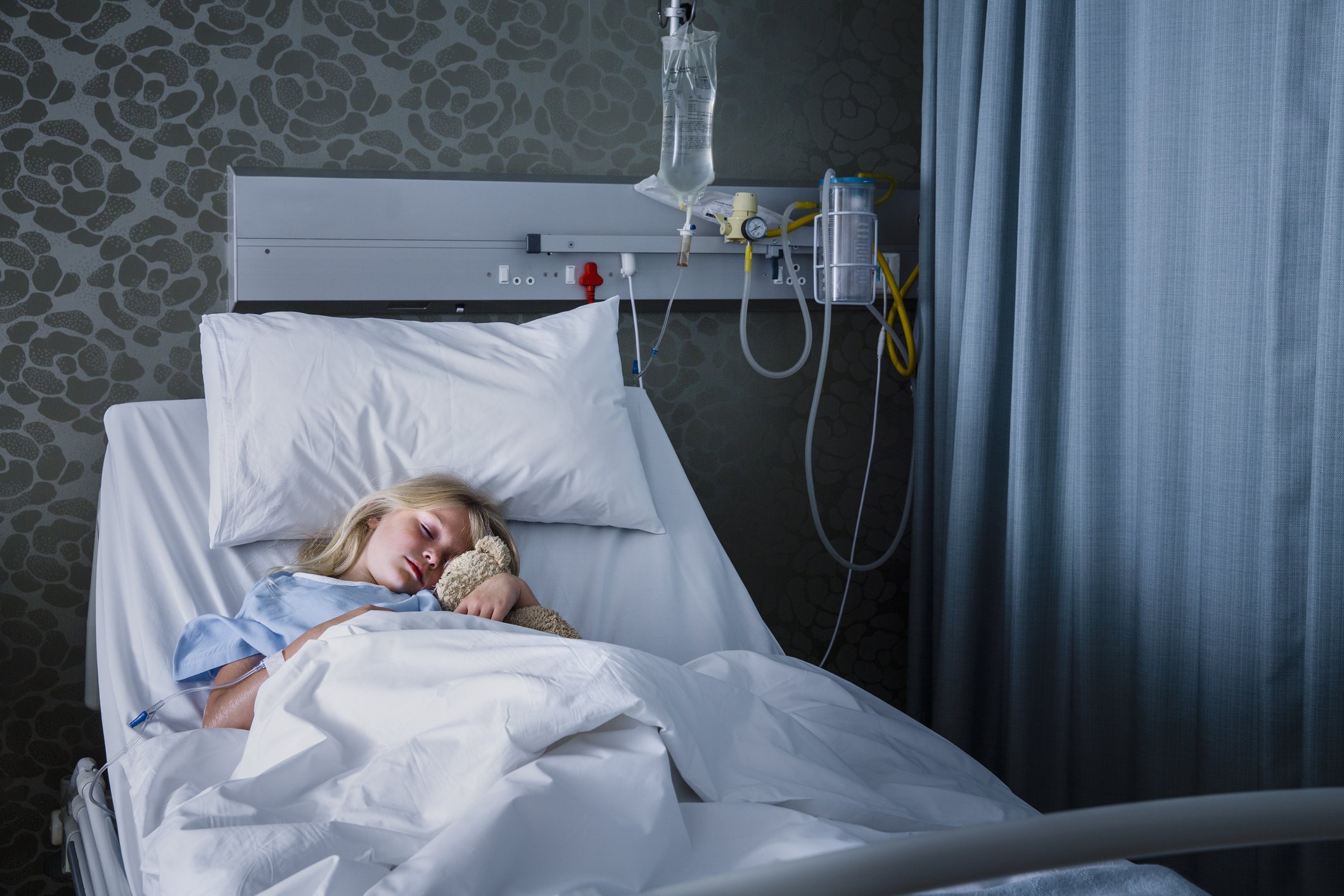 Kleines Mädchen und ein Teddybär in einem Krankenhausbett I Quelle: Getty Images