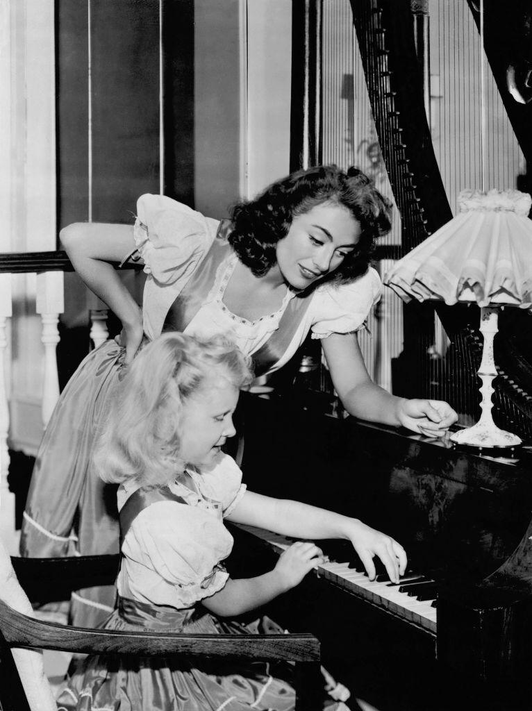 Joan Crawford helping her daughter Christina during her piano lesson in the United States on July 25, 1947 | Photo: Getty Images