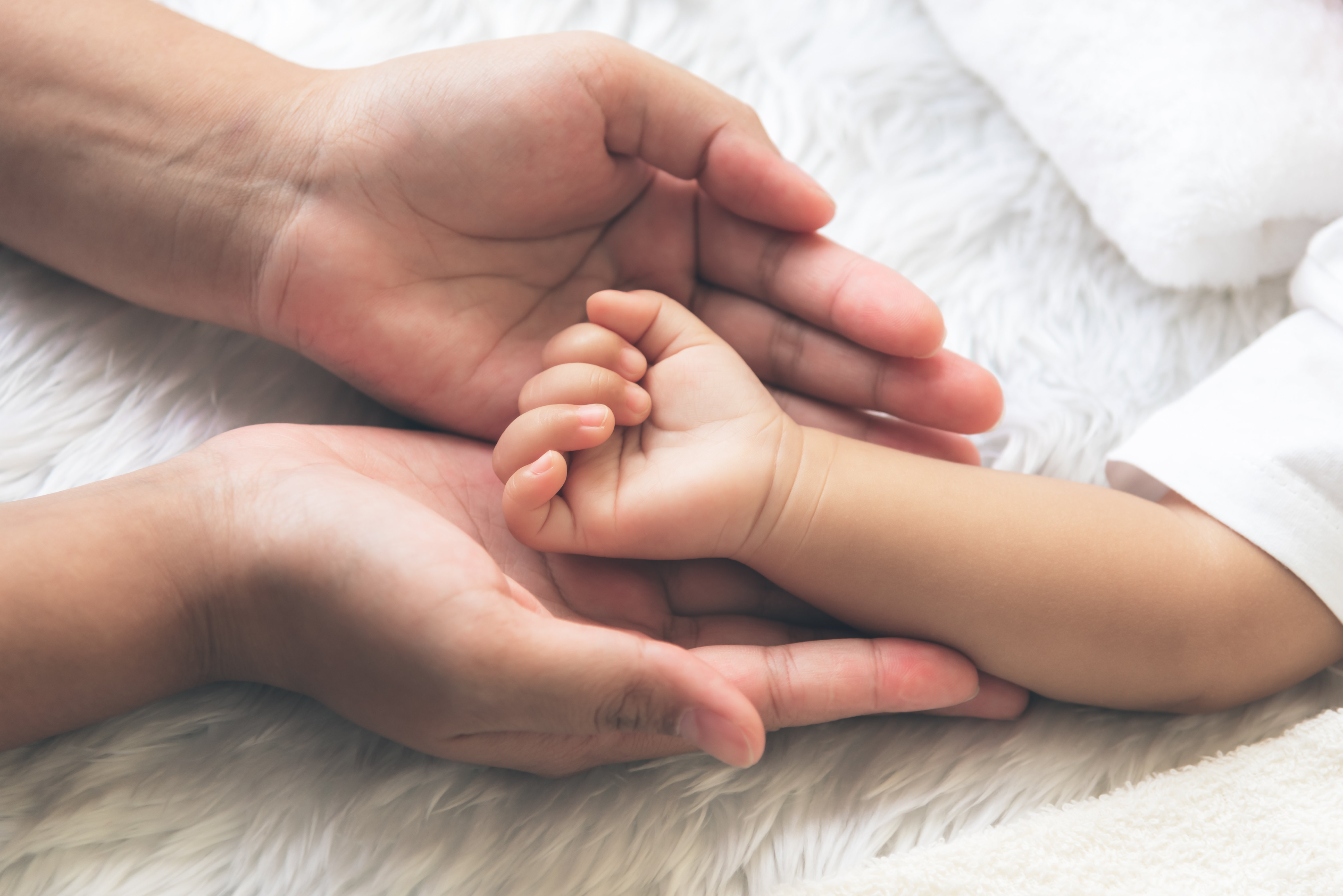 Die Hand des Babys wird auf die Hand der Mutter gelegt | Quelle: Shutterstock