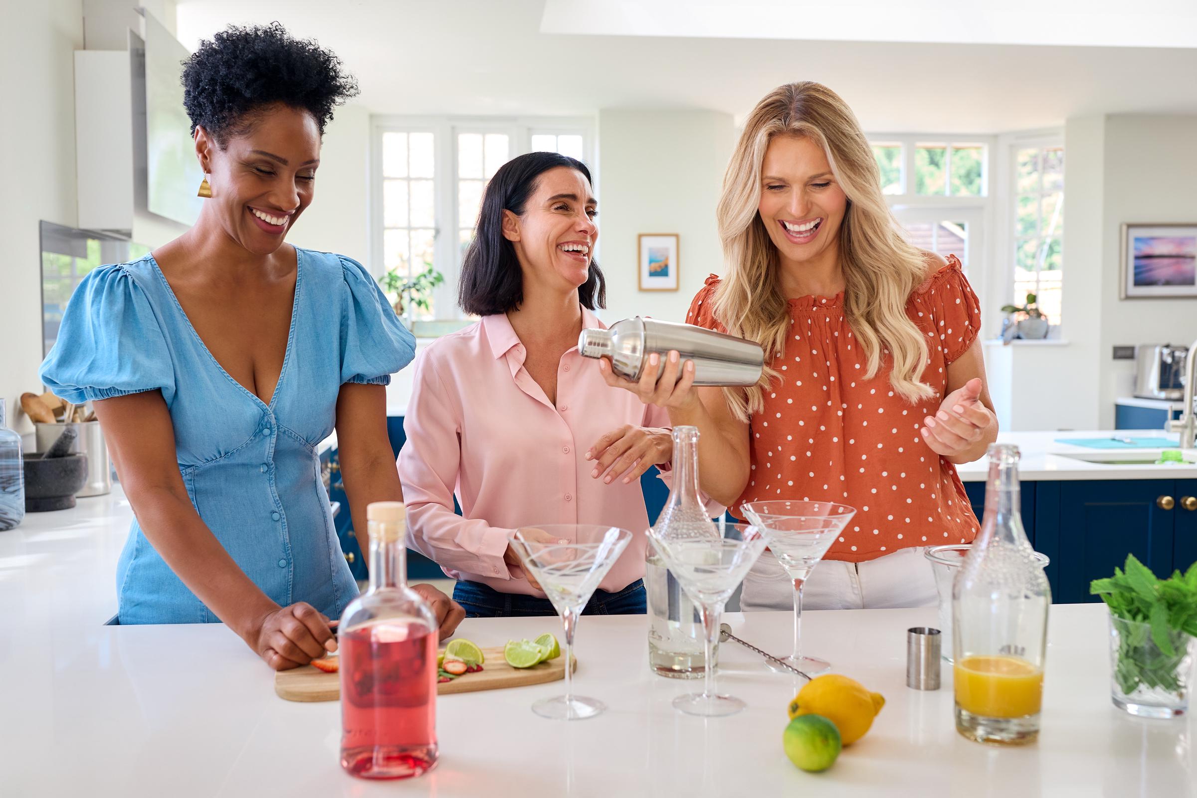 Three women friends having fun mixing cocktails together | Source: Getty Images