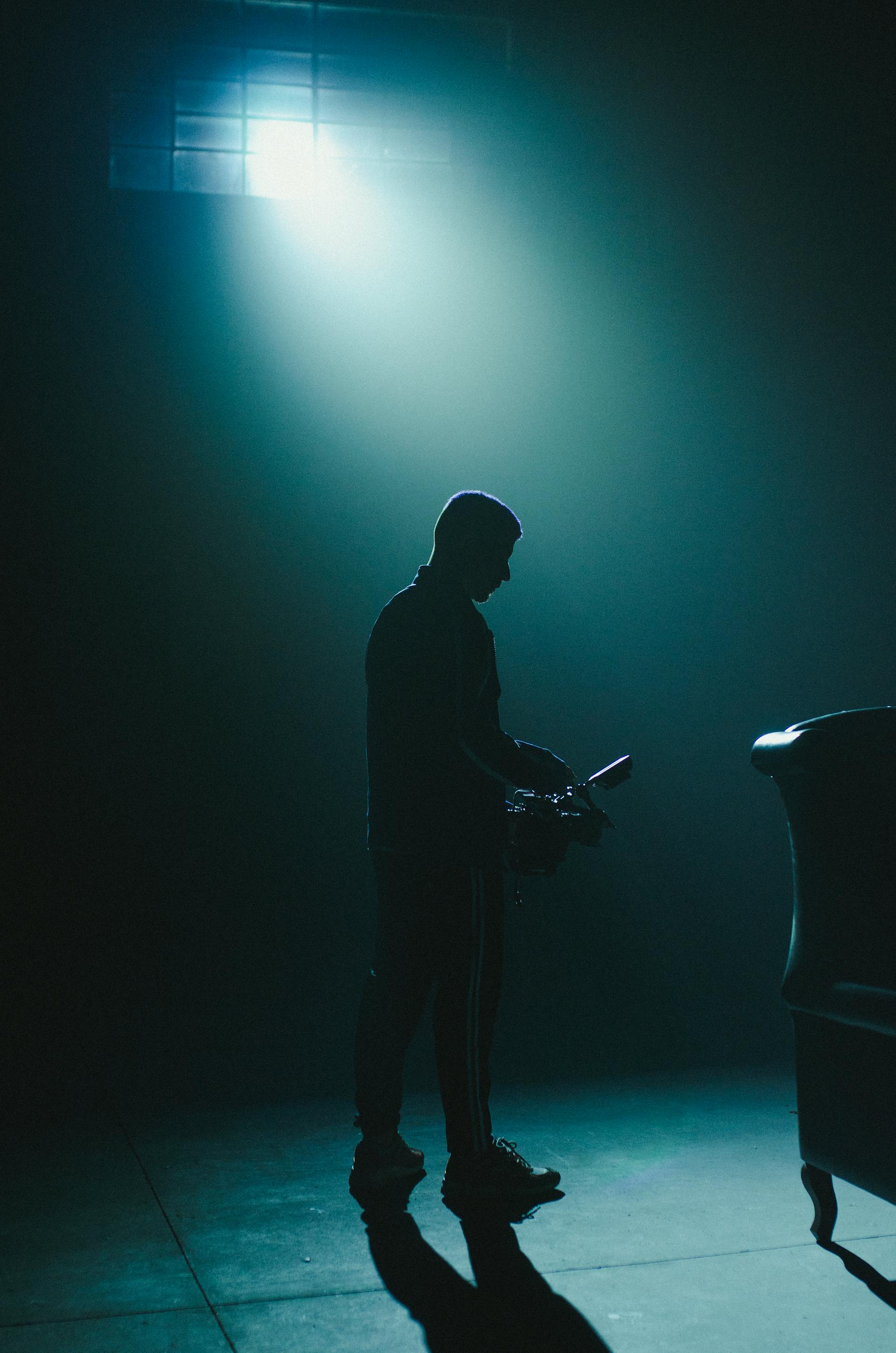 A silhouette of a man standing in a dark room | Source: Pexels