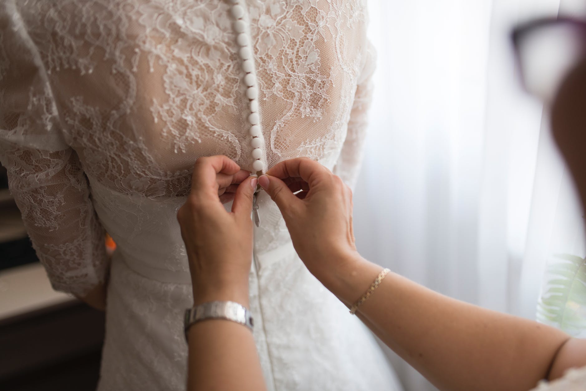 Una mujer ayuda a la novia a abrochar su vestido. | Foto: Pexels