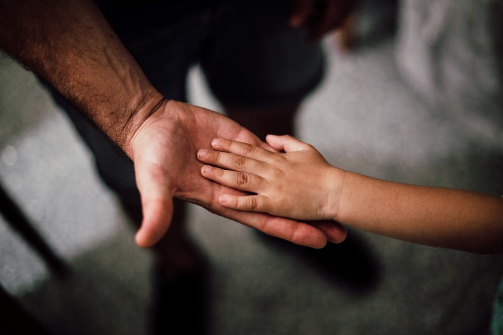 Vater hält Hand eines Kindes - Foto: Pexels