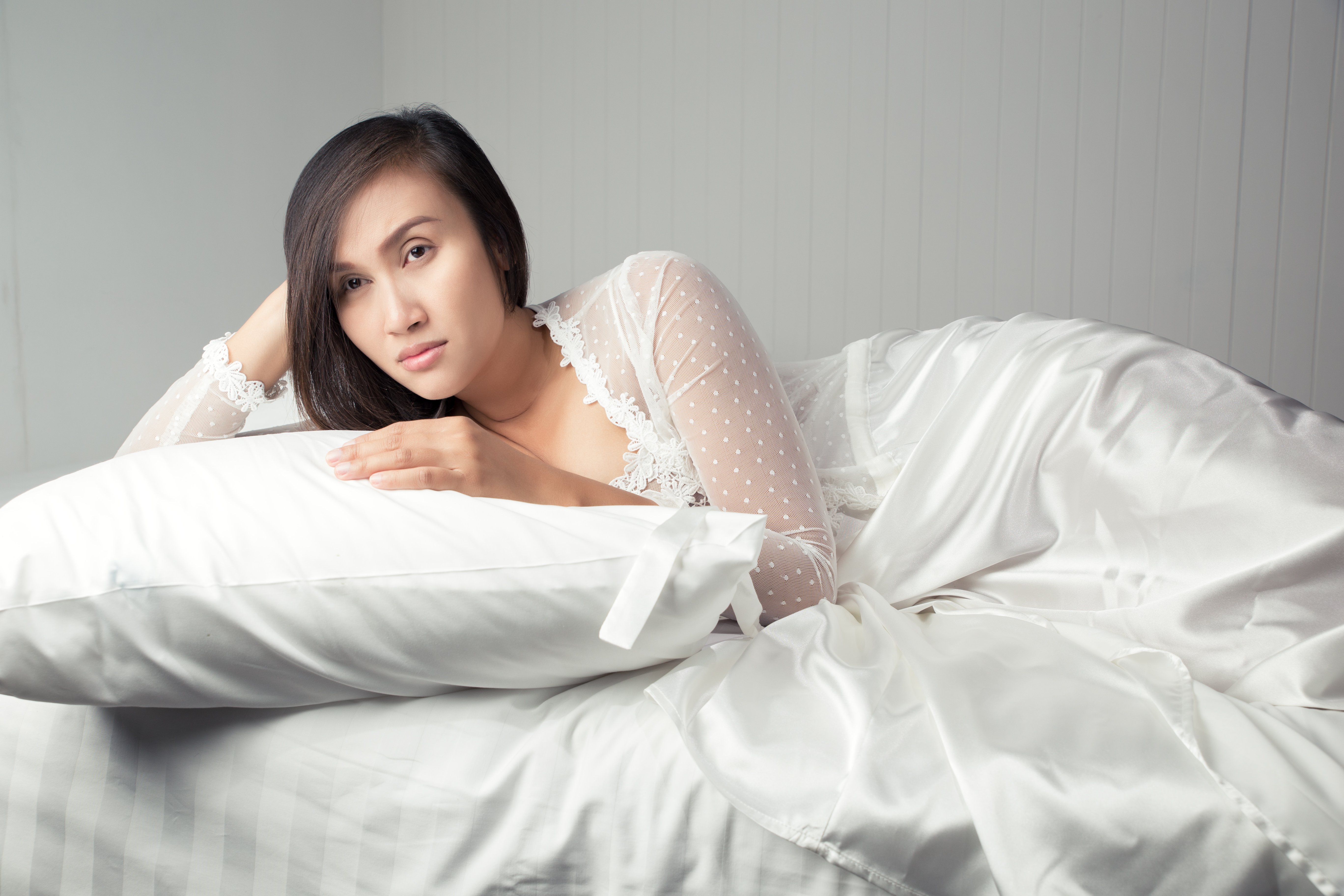 Woman showcasing luxurious bedding. | Source: Getty Images
