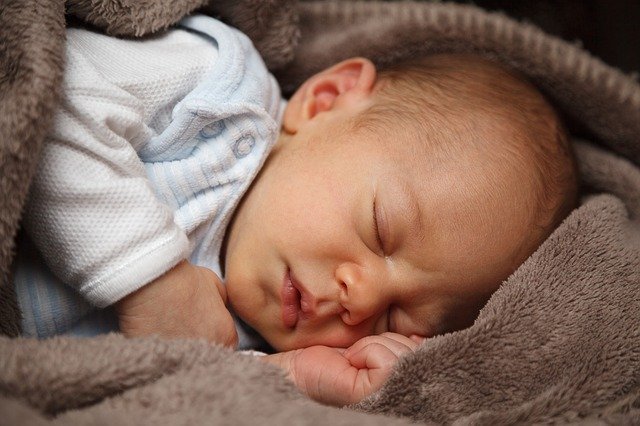 Newborn baby sleeps in gray blanket | Photo: Pixabay
