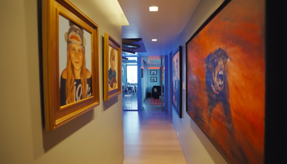 The lower level doubles as a deeply personal art gallery, with family portraits mixed among larger contemporary works. Sherman's art helps ensure the home never feels like a showroom. | Source: YouTube/Architectural Digest