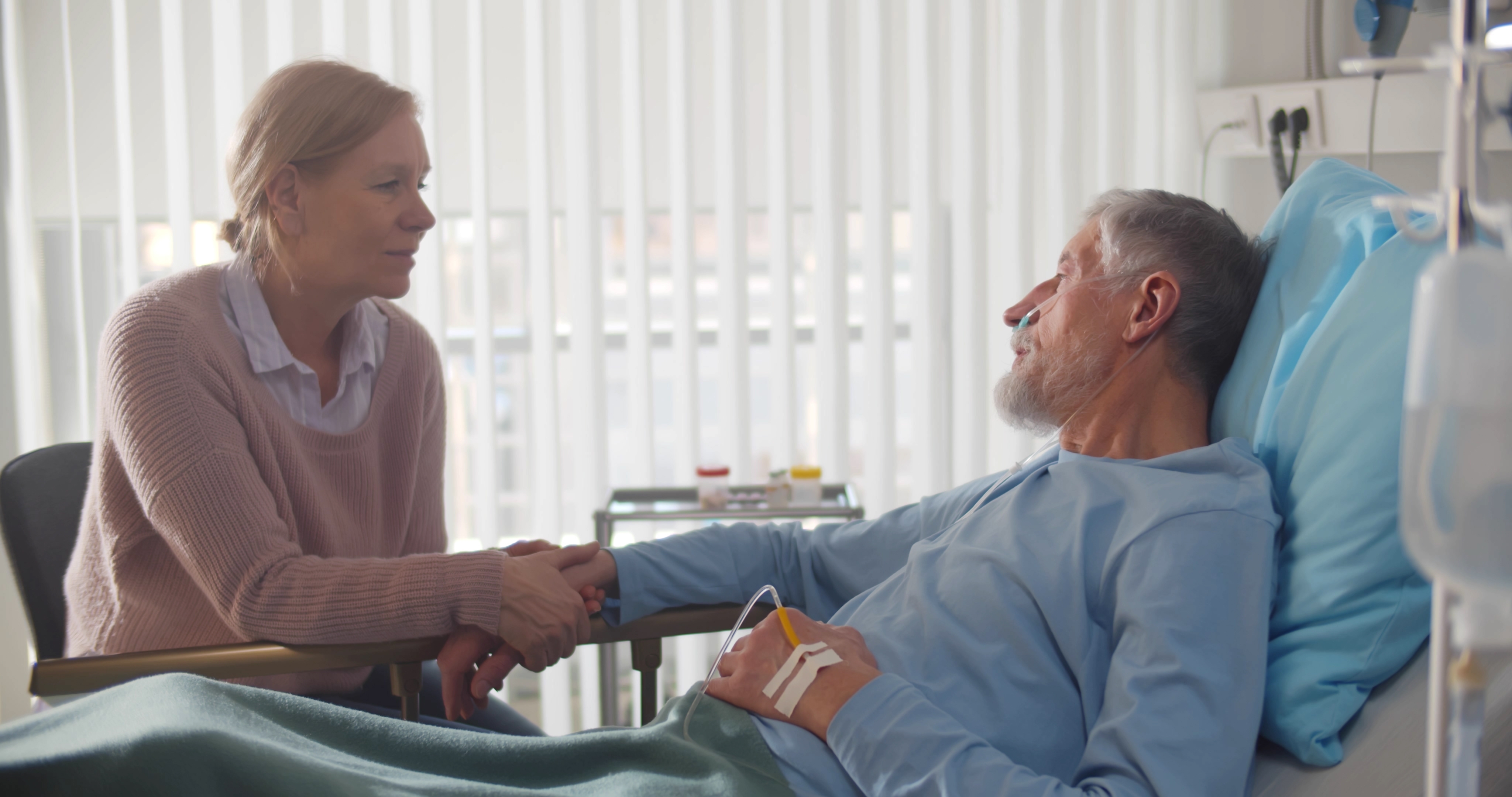 A wife holding her ailing husbands hand in the hospital | Source: Shutterstock