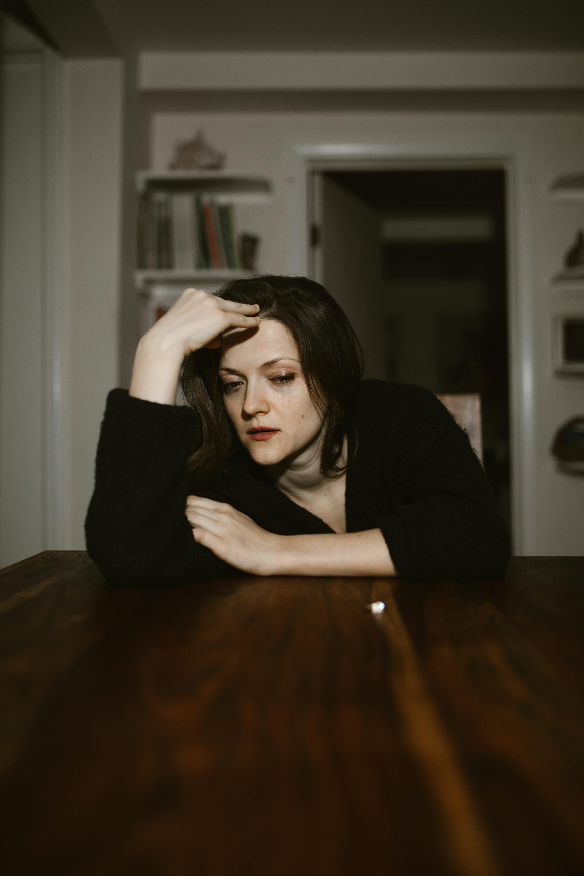 A devastated woman cries while leaning on a wooden table | Source: Pexels