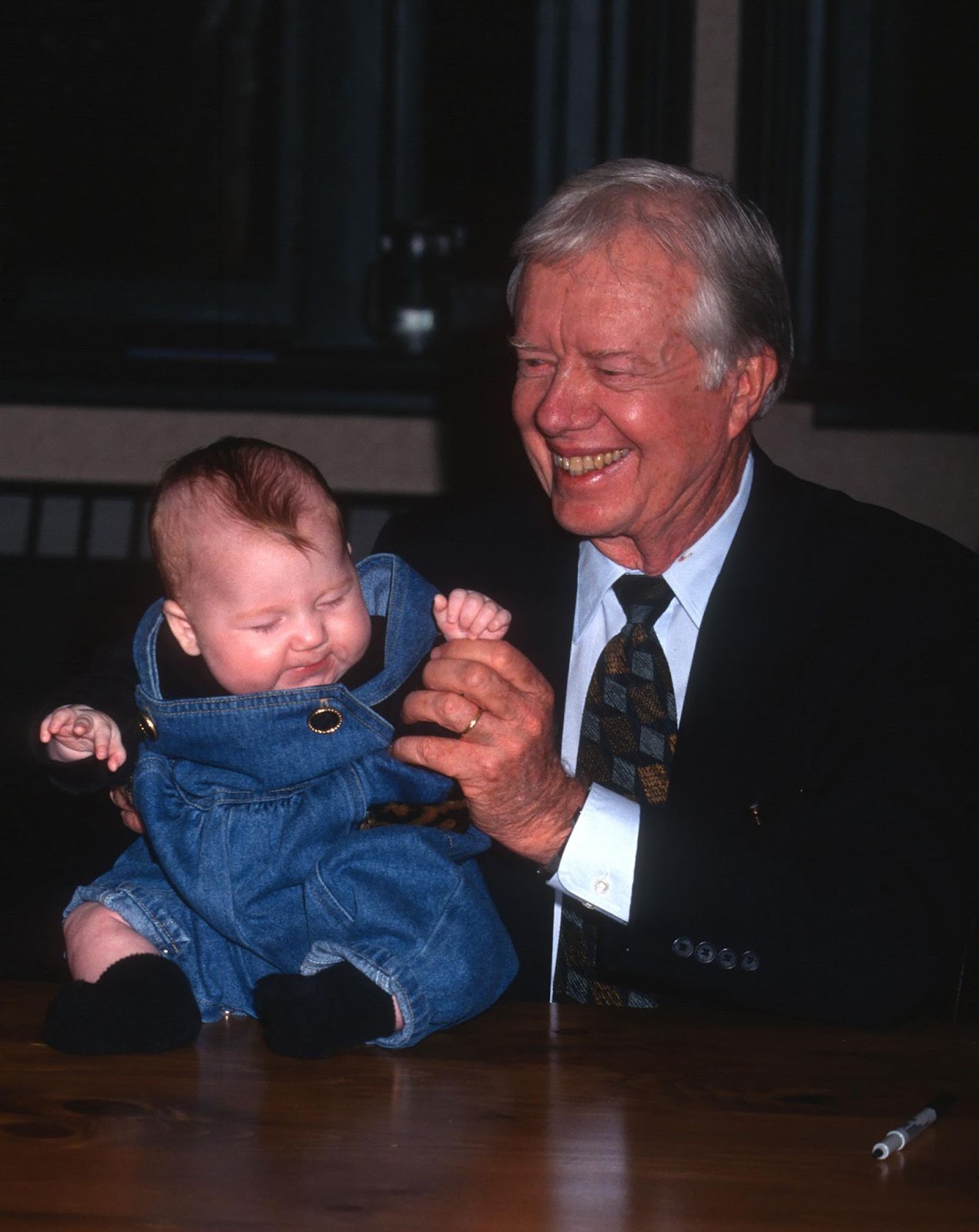 Jimmy Carter holding a baby while at "The Little Baby Snoogle-Fleejer" book party on December 13, 1995, in New York. | Source: Getty Images