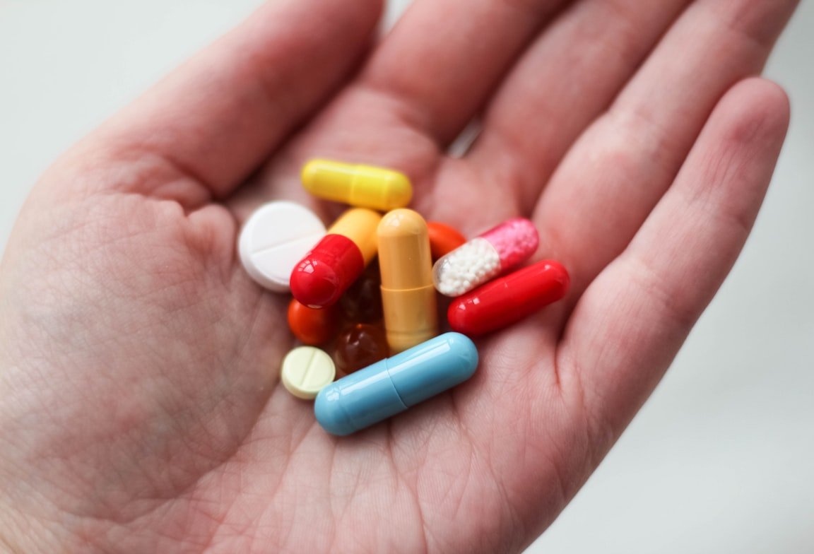 Algunas cápsulas y tabletas de medicamentos en una mano. | Foto: Unsplash