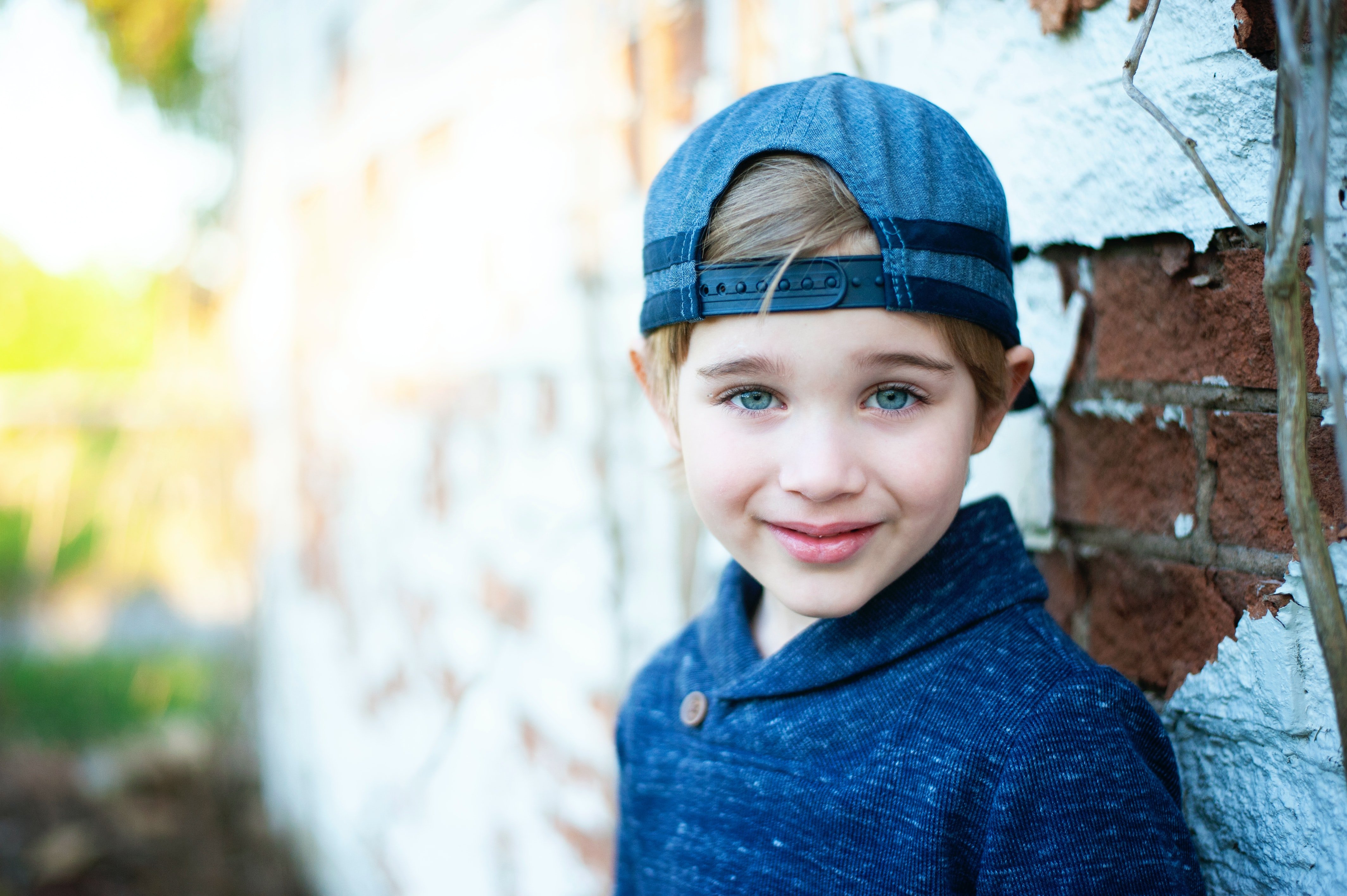Un niño pequeño con una gorra, sonríe timidamente. | Foto: Unsplash