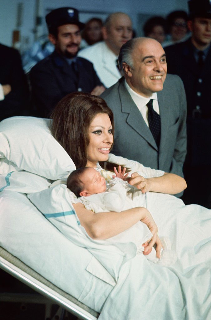 Sophia Loren has a pat on the cheek for her husband, film producer Carlo Ponti, and a smile for her son, Carlo Ponti Jr., as the baby makes his first public appearance in Cantonal Hospital. | Source: Getty Images