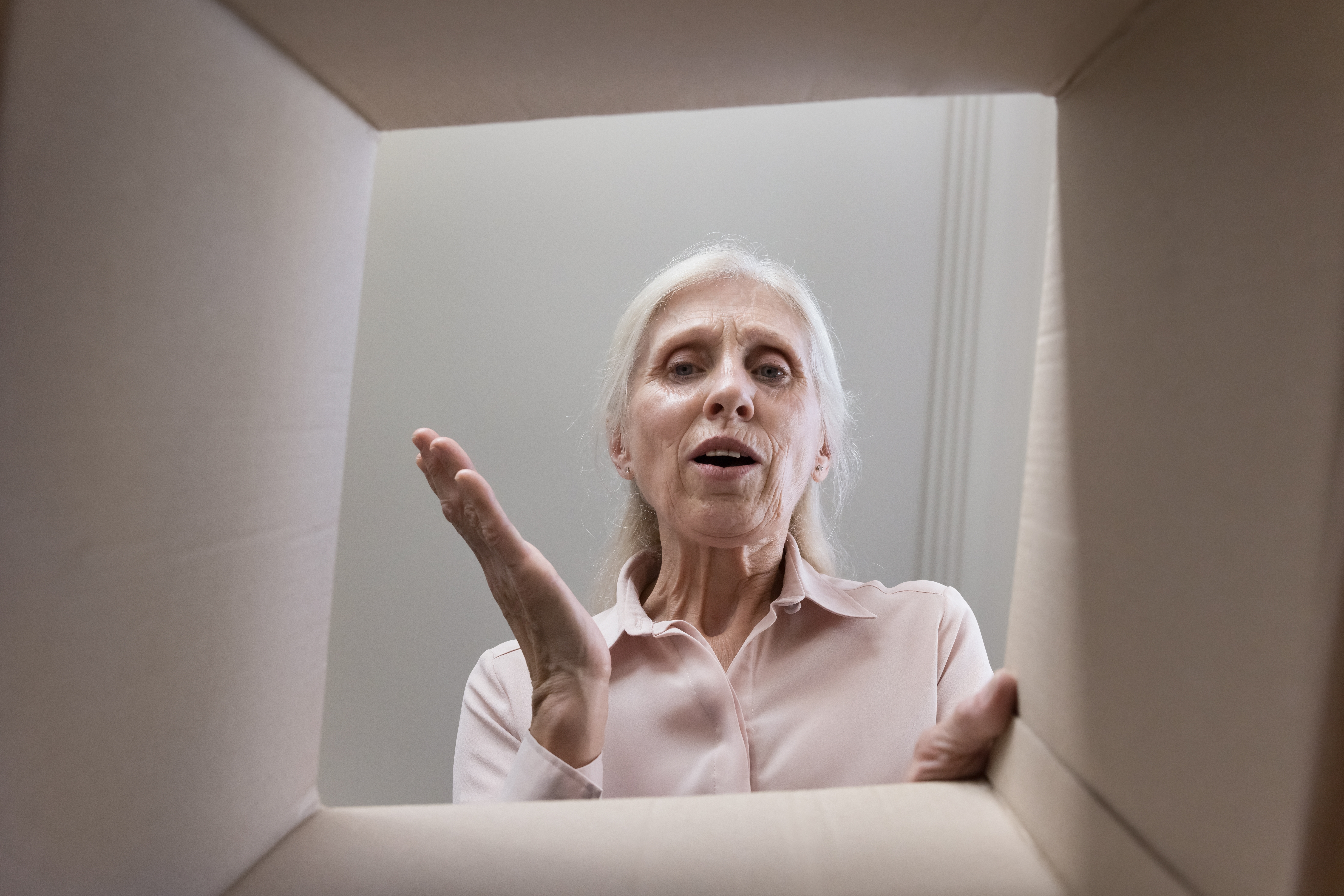 Senior woman looking inside a cardboard box | Source: Shutterstock