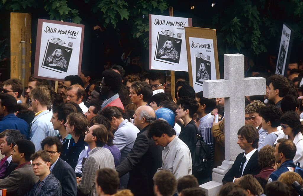 Une foule de personnes en deuil se rassemblent dans un cimetière de Montrouge, en France, pour rendre hommage à la bande dessinée populaire Coluche. | Photo : Getty Images