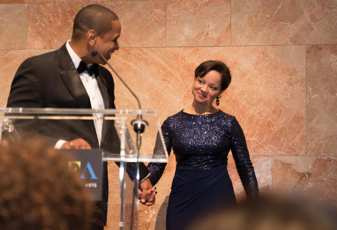 Justin Fairfax speaks at an event while holding hands with Cerina Fairfax, who looks on, during a formal gathering | Source: Facebook/justin.fairfax.2025