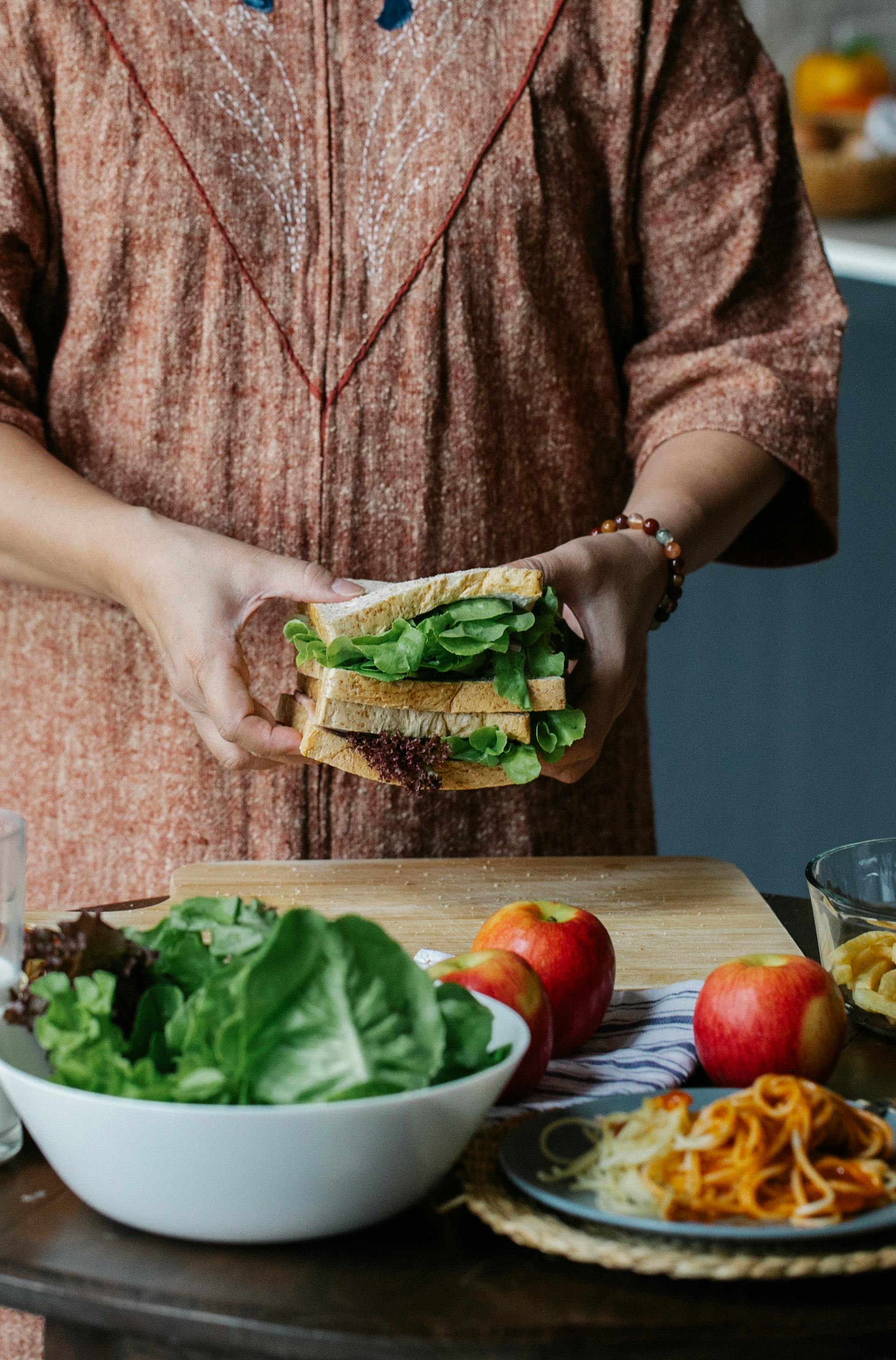 A closeup shot of a woman making a sandwich in the kitchen | Source: Pexels