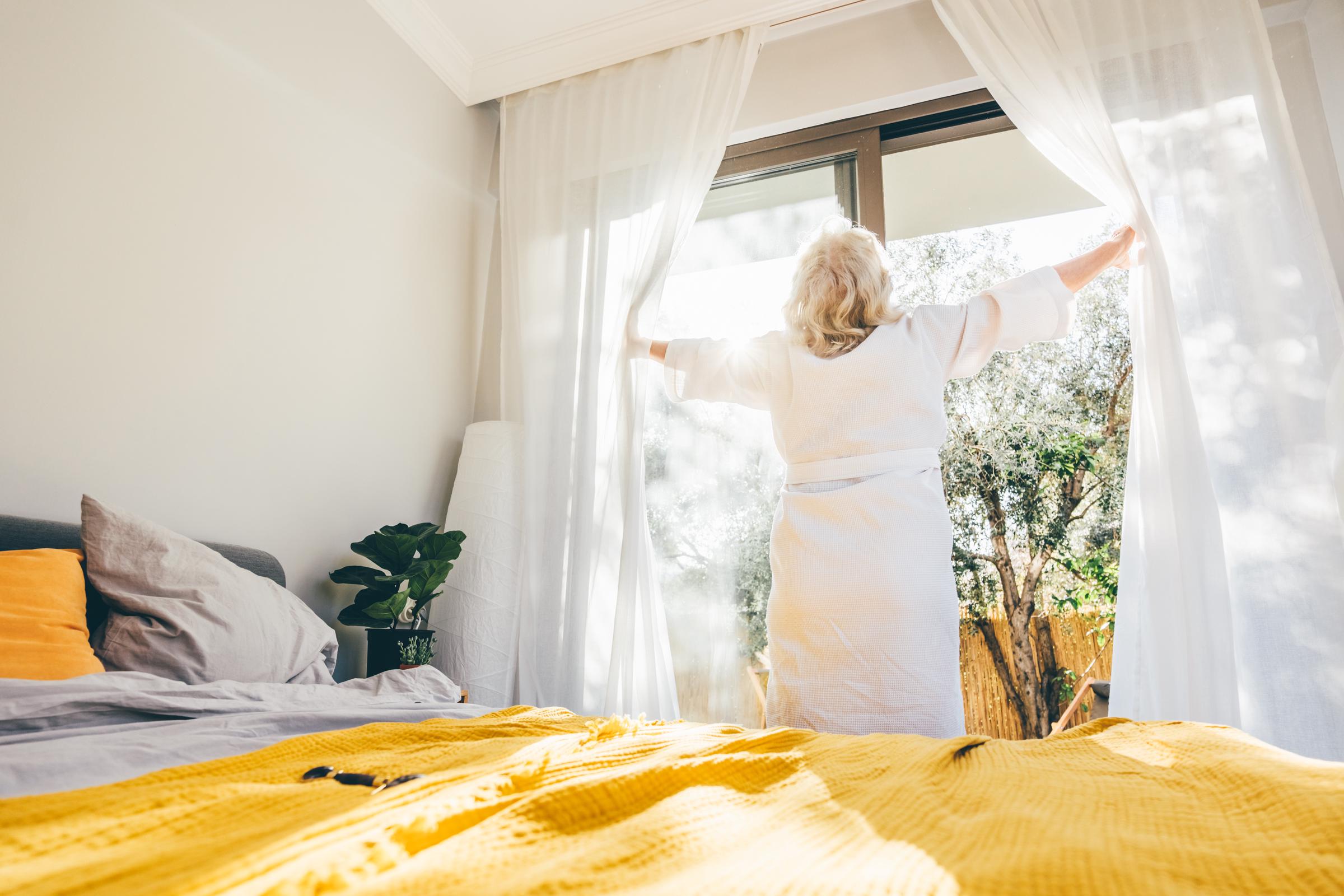 A woman opening the curtains in her room | Source: Getty Images