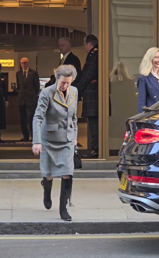 Princess Anne exits The Cumberland Hotel in London and steps confidently toward the street, her composed expression and signature brisk stride visible as she carries a black handbag and showcases her elegant knee-high suede riding boots. | Source: Instagram/kingsguardchannel