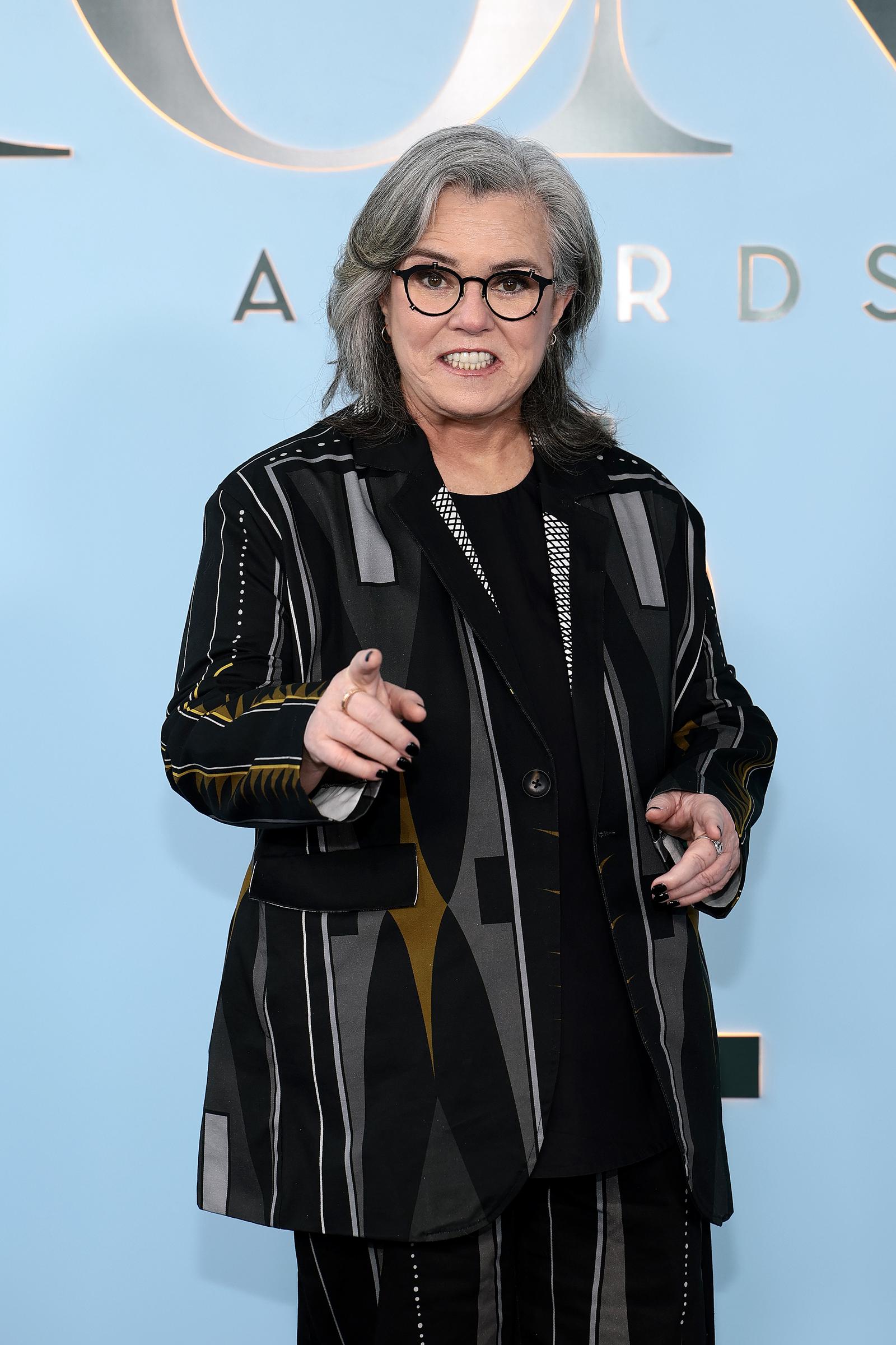 Rosie O'Donnell points toward photographers while posing on the red carpet. Images like this helped fuel online discussions as viewers began focusing on her facial features.