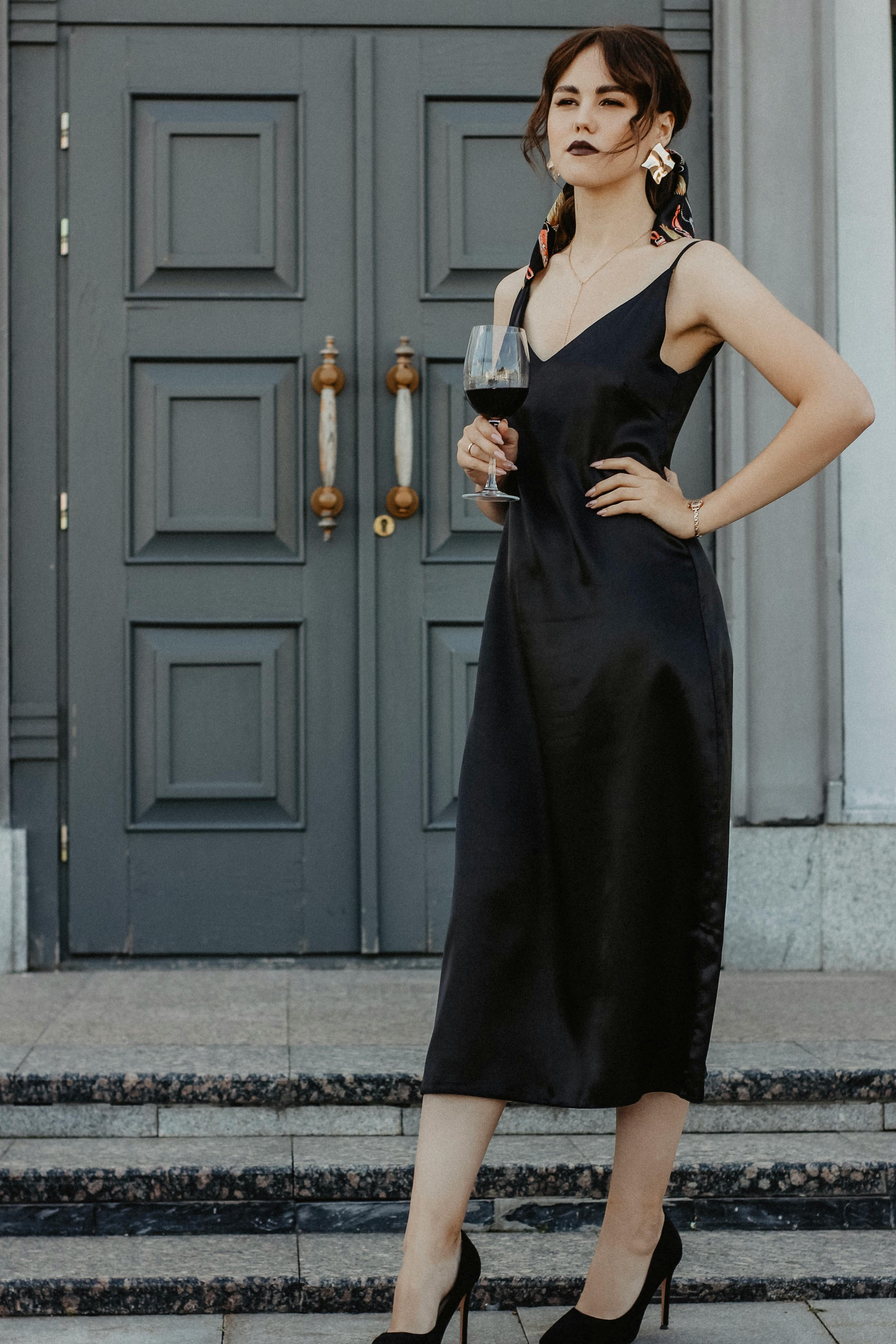 A woman in a black dress holding a glass of wine | Source: Pexels