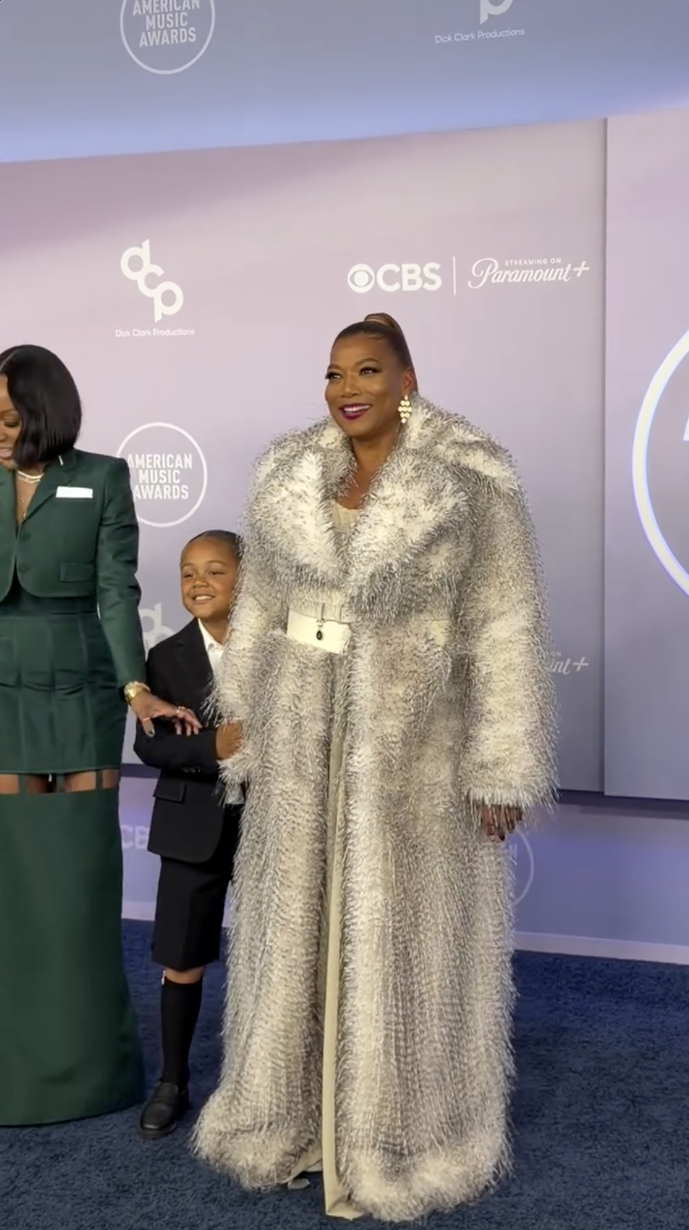 Rebel Nichols Owens smiles beside Queen Latifah as Eboni Nichols steps into frame beneath the CBS and Paramount+ logos at the AMAs. | Source: Instagram/perezhilton