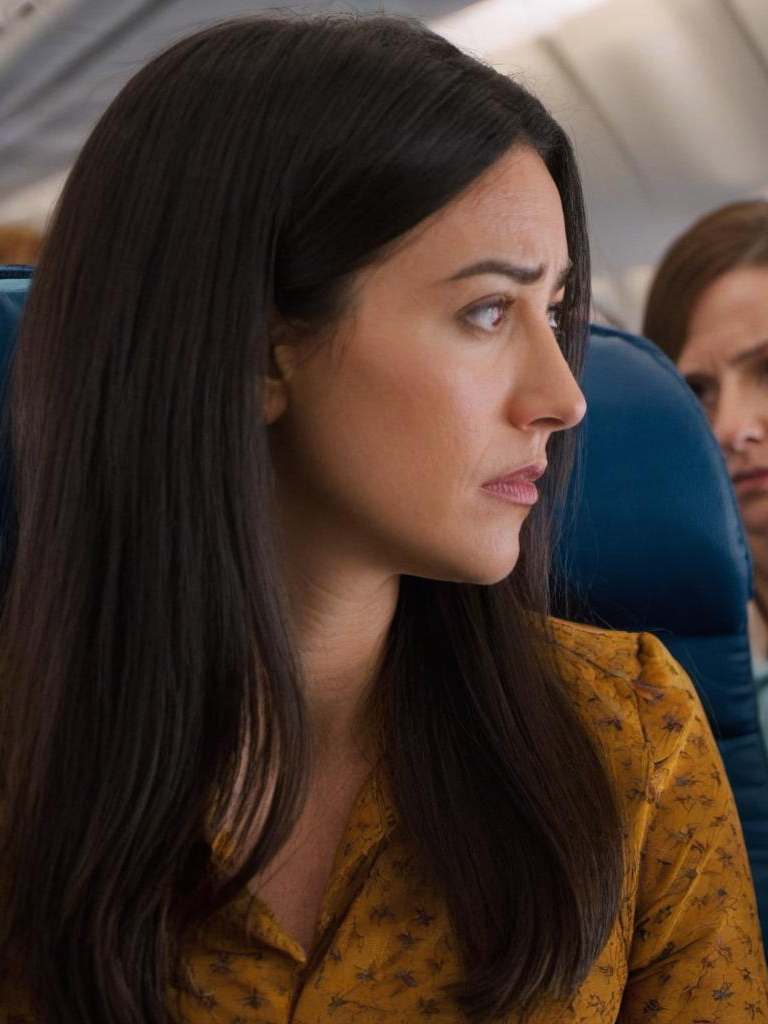 A woman looking with concern at the passenger seated beside her | Source: Midjourney