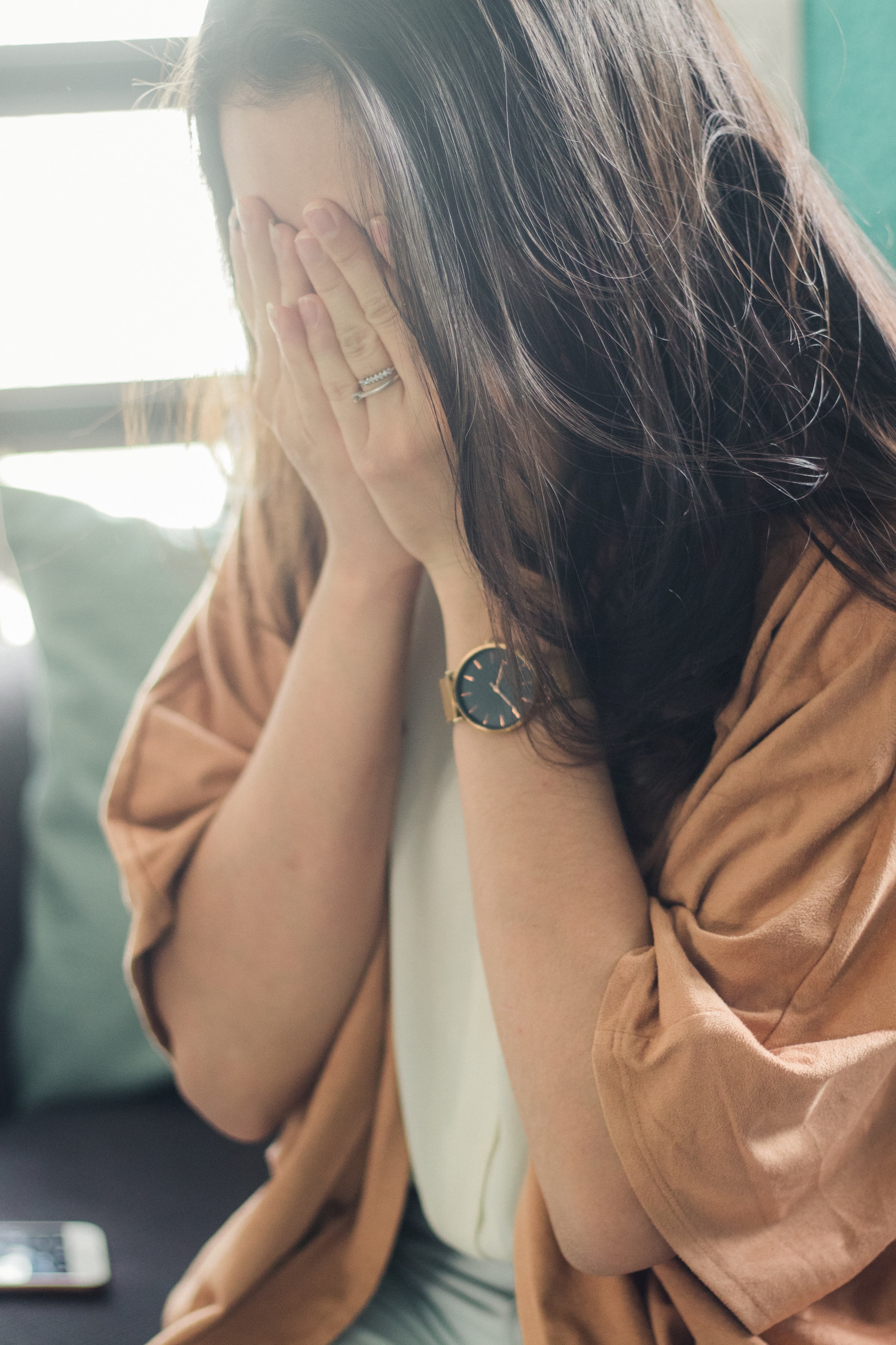 A depressed woman covers her face with her hands | Source: Unsplash