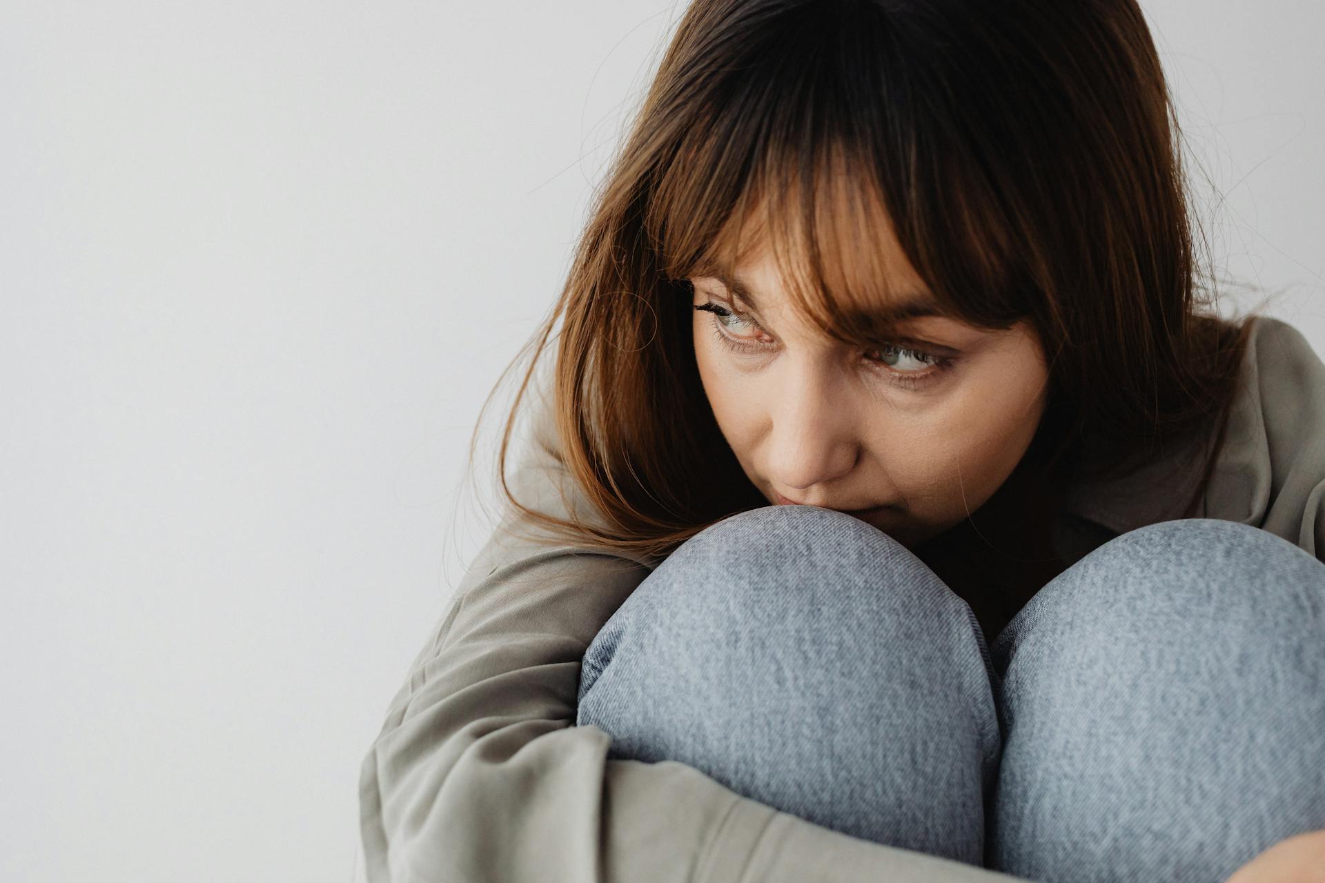 A distressed woman huddled on the chair and looking to her side | Source: Pexels