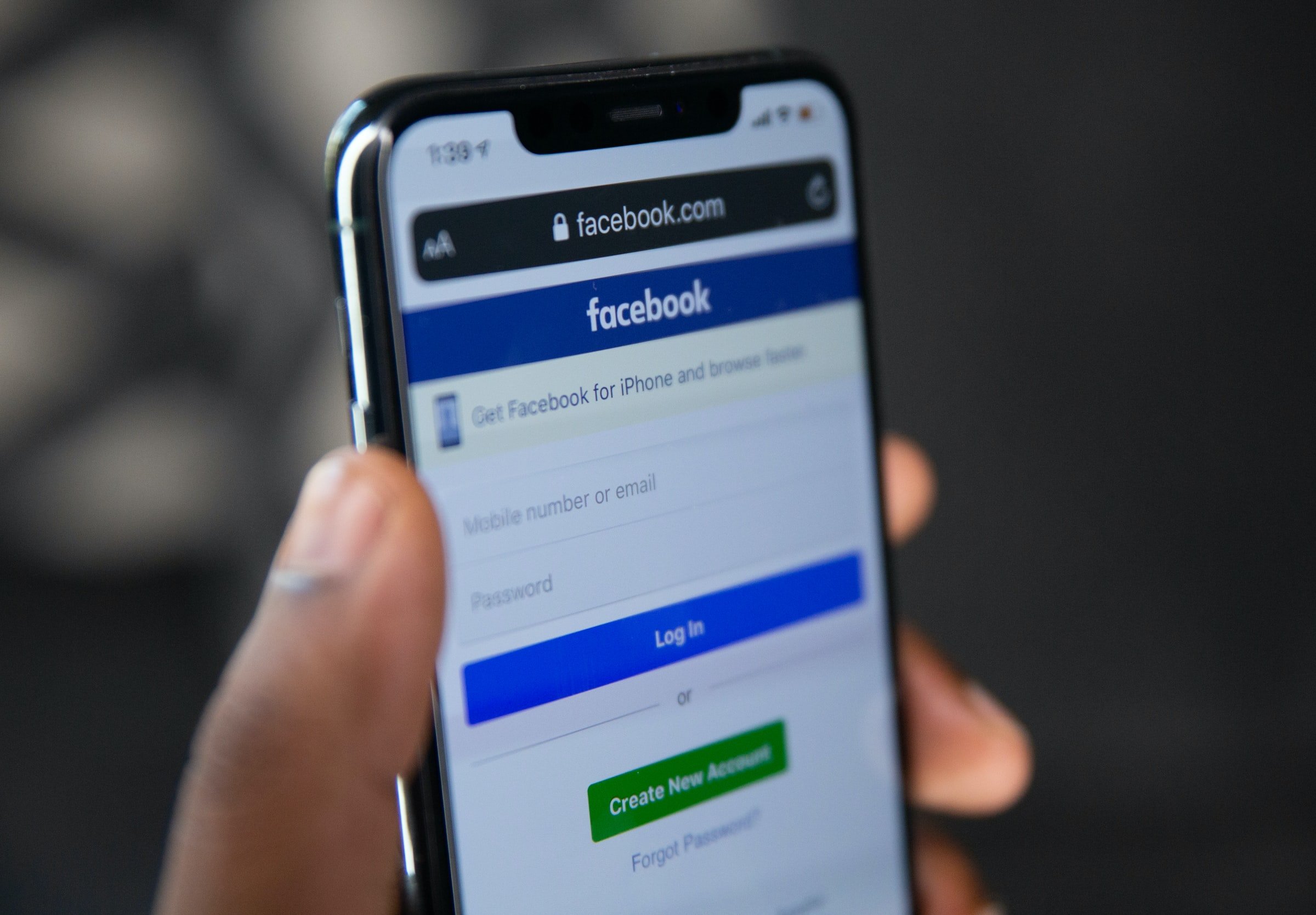 Person holding phone displaying Facebook's website. | Source: Unsplash