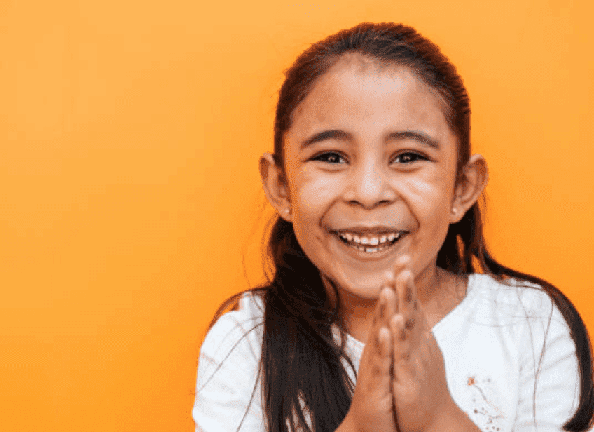 A young girl smiles as she holds her hands in together in prayer, Mexico | Source: Getty Images